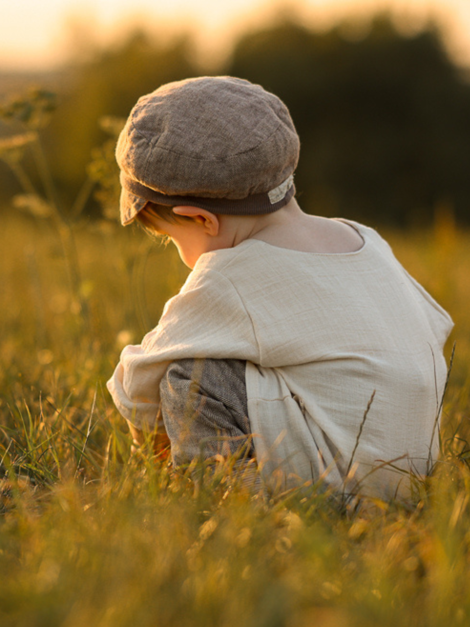 Ein Kleinkind trägt das Hemdchen Bio-Musselin - Natur, ein locker geschnittenes, hautfreundliches Oberteil aus GOTS-zertifiziertem Bio-Musselin, ideal für warme Tage, beim Spielen in einer sonnigen Wiese.