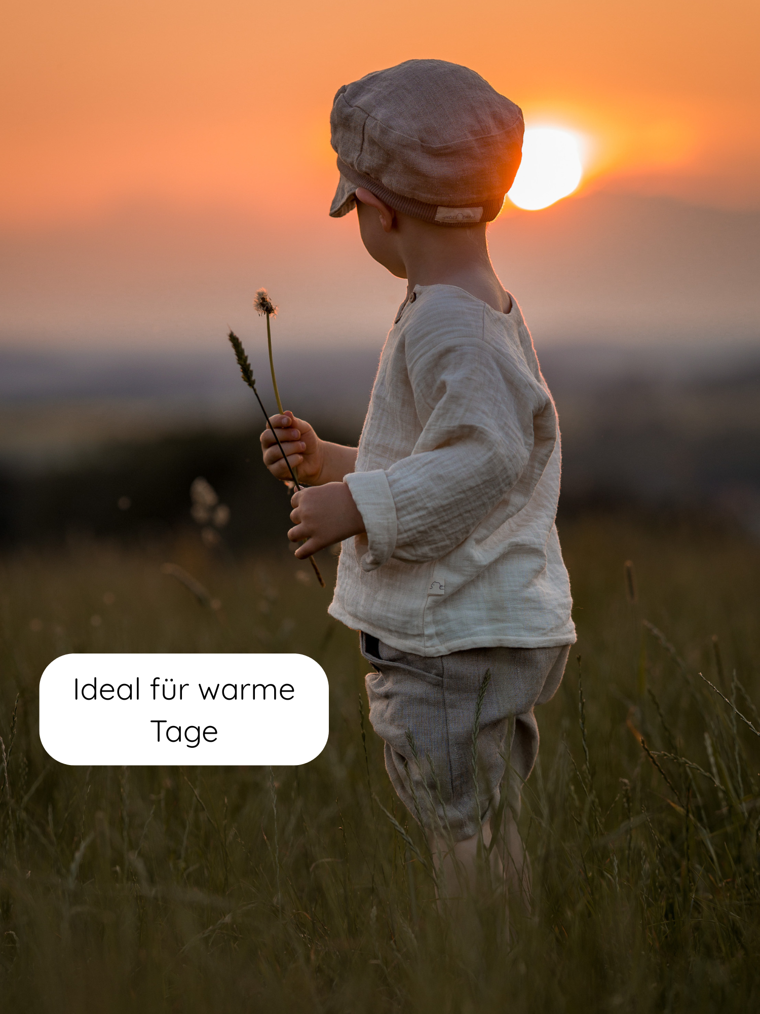 Kleinkind in lockerem Hemdchen Bio-Musselin - Natur aus GOTS-zertifiziertem Musselin, ideal für warme Tage, steht im Gras und hält einen Löwenzahn. Perfekt für Spiel und Bewegung.