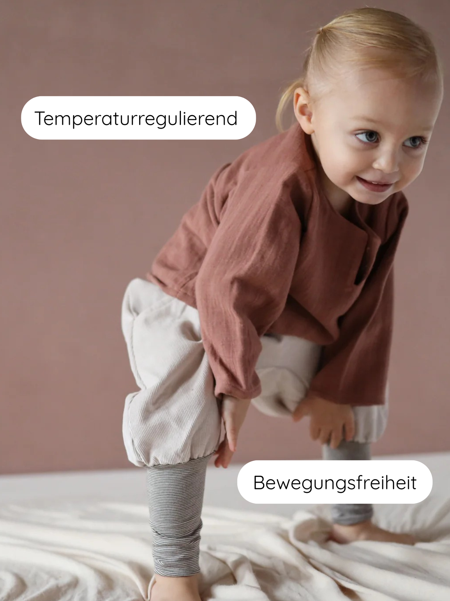 Ein Kleinkind trägt das Hemdchen Bio-Musselin - Zimt, ein locker geschnittenes, atmungsaktives Oberteil in rustbrauner Farbe, ideal für Bewegungsfreiheit und warmes Wetter.