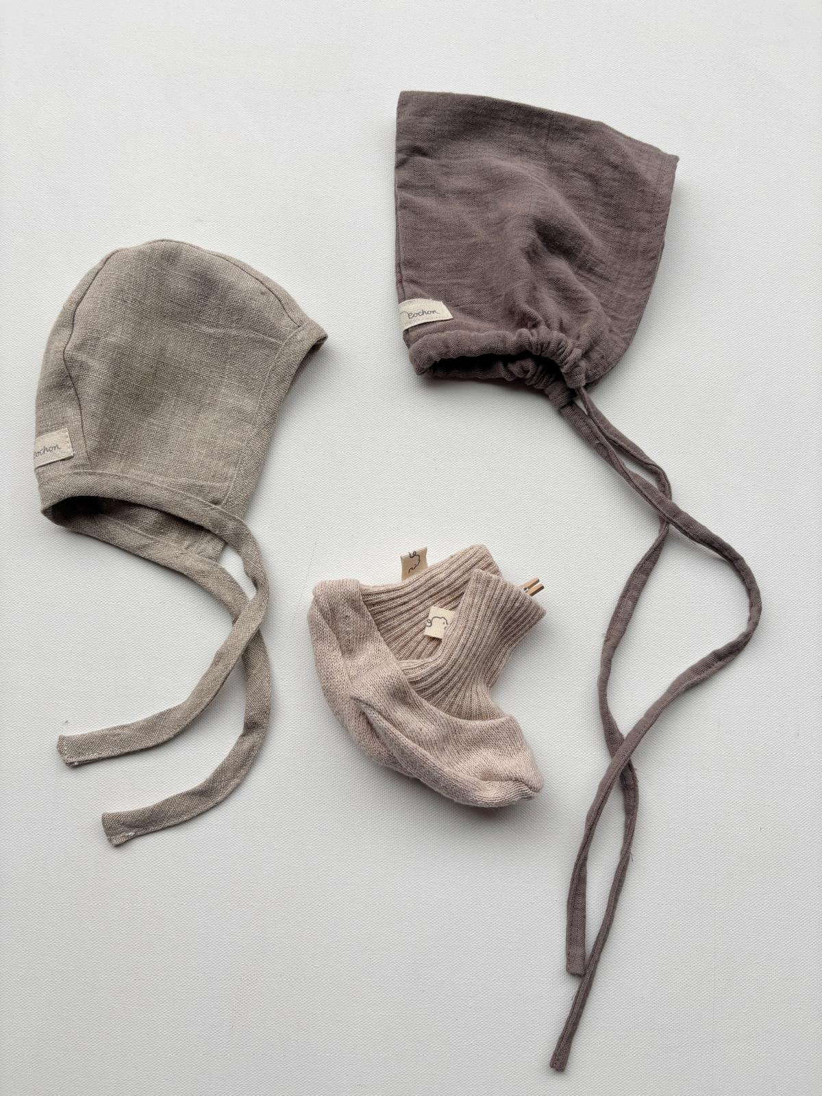 Set 6 Zwergenmütze, Schühchen und Häubchen in Gr 0M, bestehend aus mehreren Babymützen und Socken auf weißem Untergrund, mit Nahaufnahmen von Stoff und Etikett.