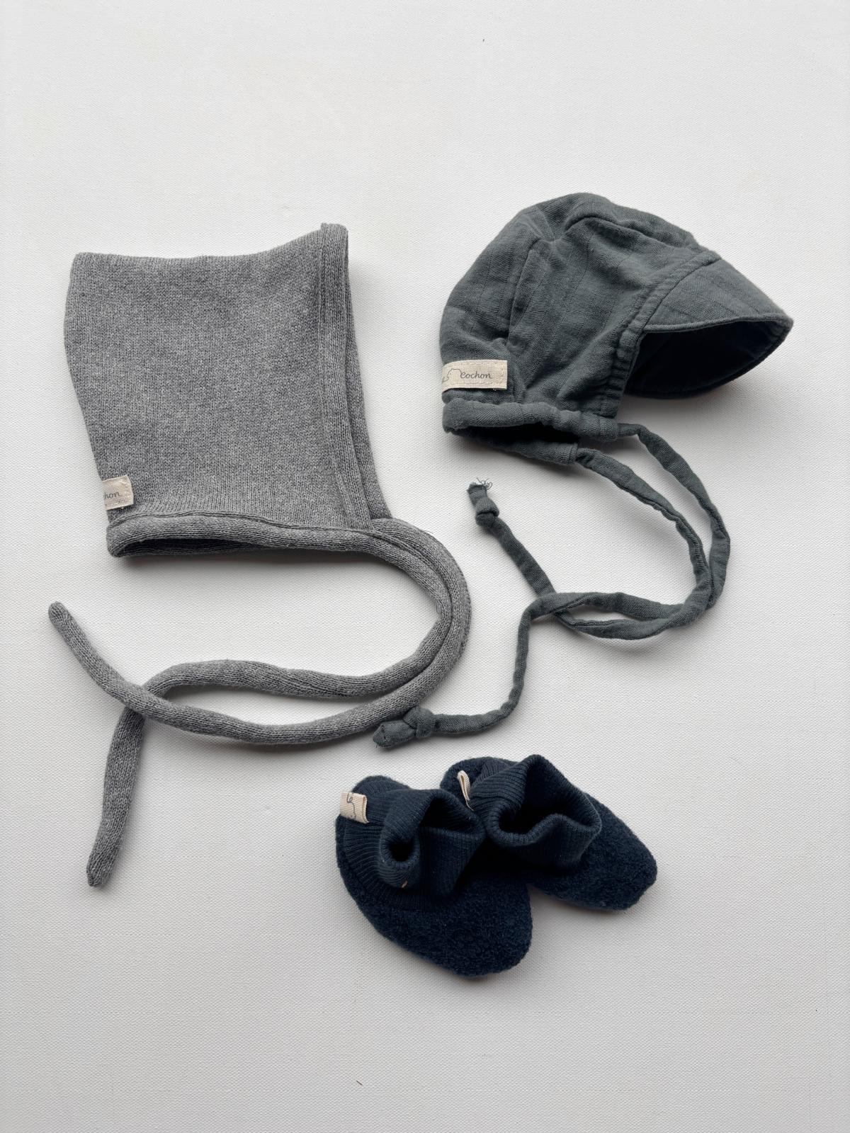 Set 11 Schirmmütze, Zwergenmütze und Schühchen in Gr 0M; zeigt eine graue Mütze mit Bändern und passendes Paar Schuhe auf einer weißen Fläche. Zustand: neu.
