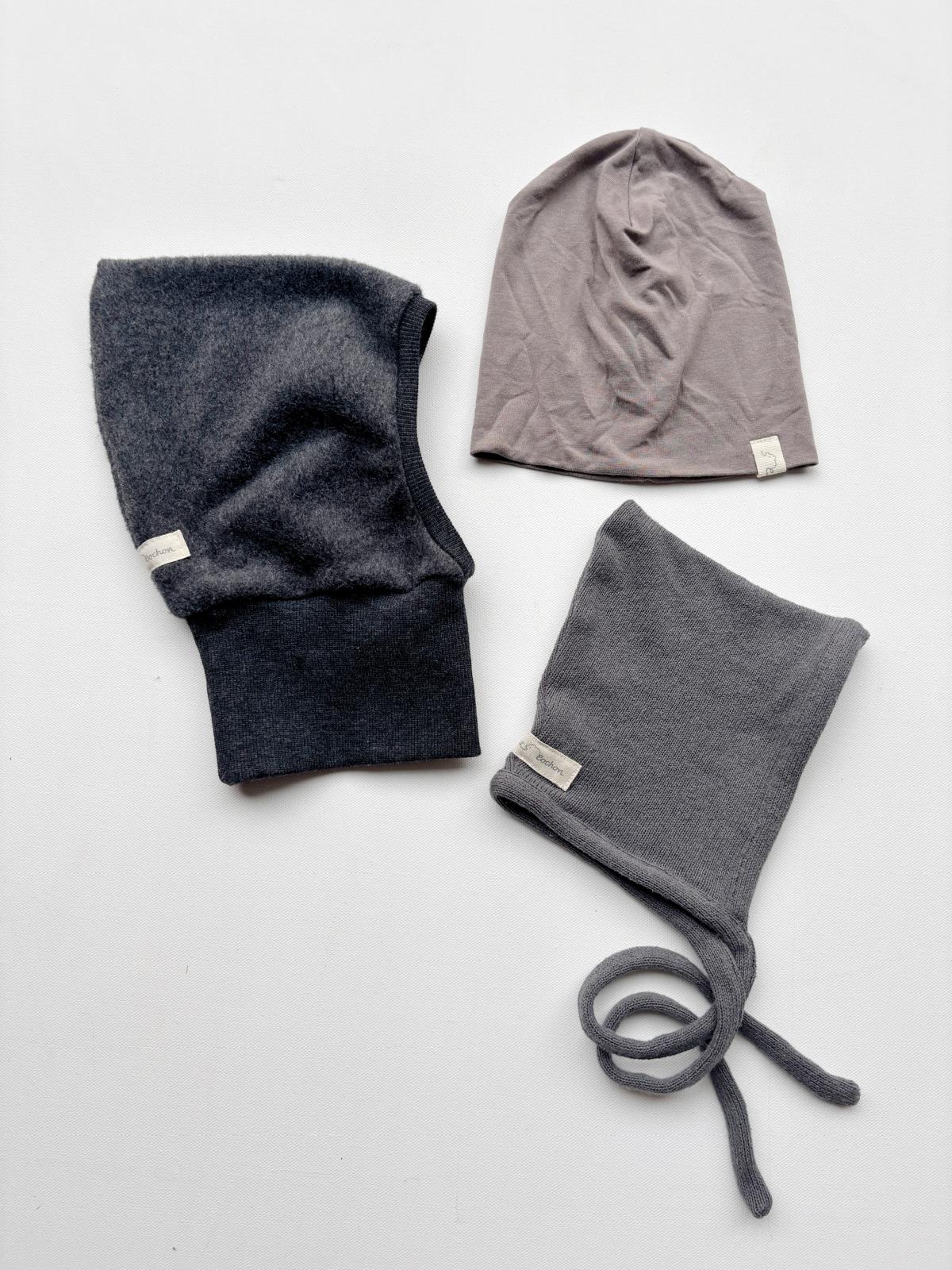 Set 14 Beanie, Zwergenmütze und Schlupfmütze Gr 0M auf weißer Fläche, zeigt eine Auswahl verschiedener Hüte mit Fokus auf gestrickte Details und Etikett.
