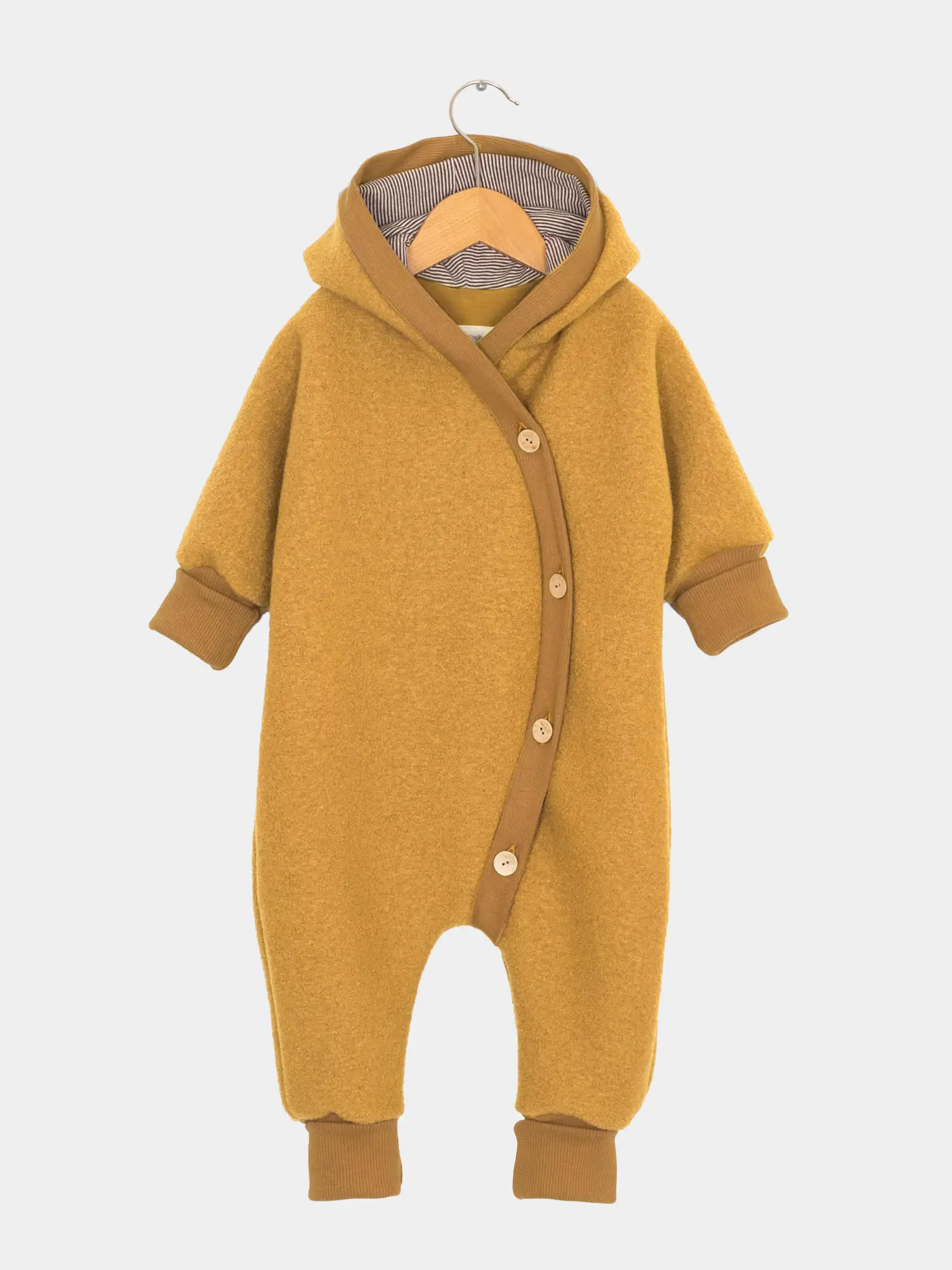 Kuschelanzug Wollwalk - Honig: Mustardgelber Baby-Overall aus weichem Wollwalk mit Kapuze, diagonal verlaufenden Holzknöpfen, gerippten Bündchen und Bio-Jersey-Futter, auf einem schlichten Holzkleiderbügel hängend.