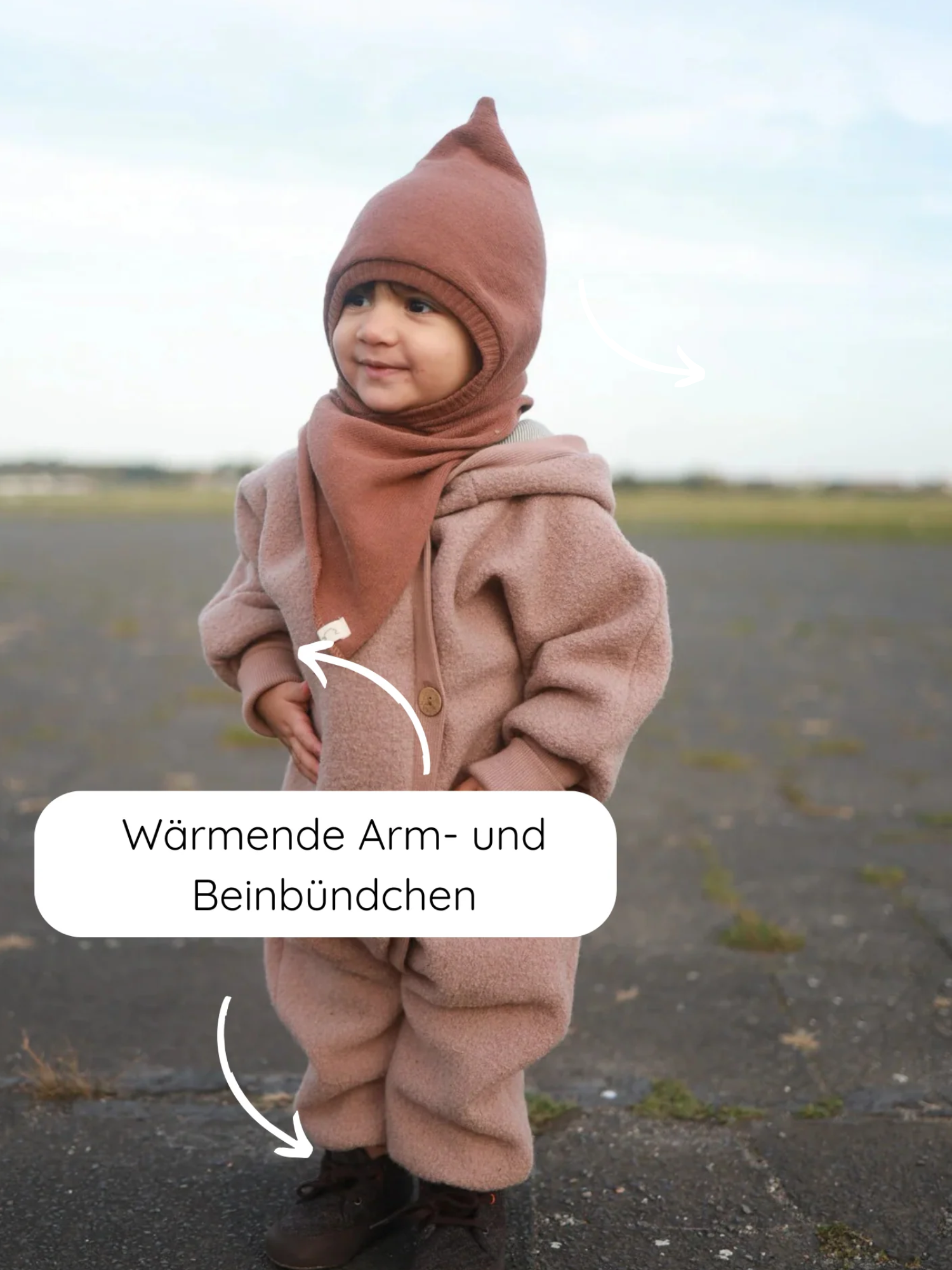 Kleinkind im Kuschelanzug Wollwalk - Puder, aus 100% Schurwolle, mit Kapuze und Krempelbündchen. Wärmende Arm- und Beinbündchen betont. Ideal für kühle Outdoor-Aktivitäten.