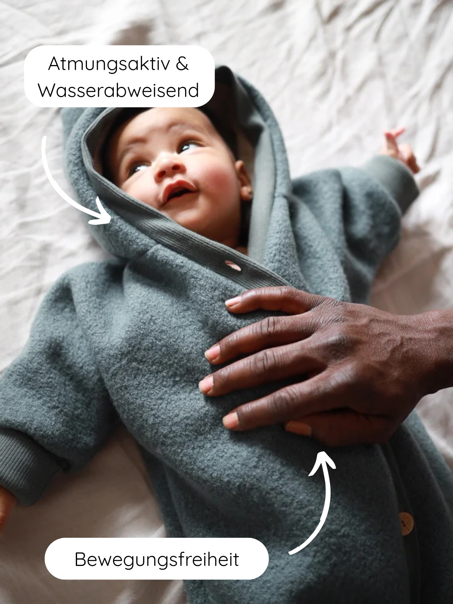 Ein Baby liegt auf einer weichen Oberfläche im Kuschelanzug Wollwalk - Taube. Der Wollwalk Overall ist atmungsaktiv, wasserabweisend und bietet Bewegungsfreiheit.