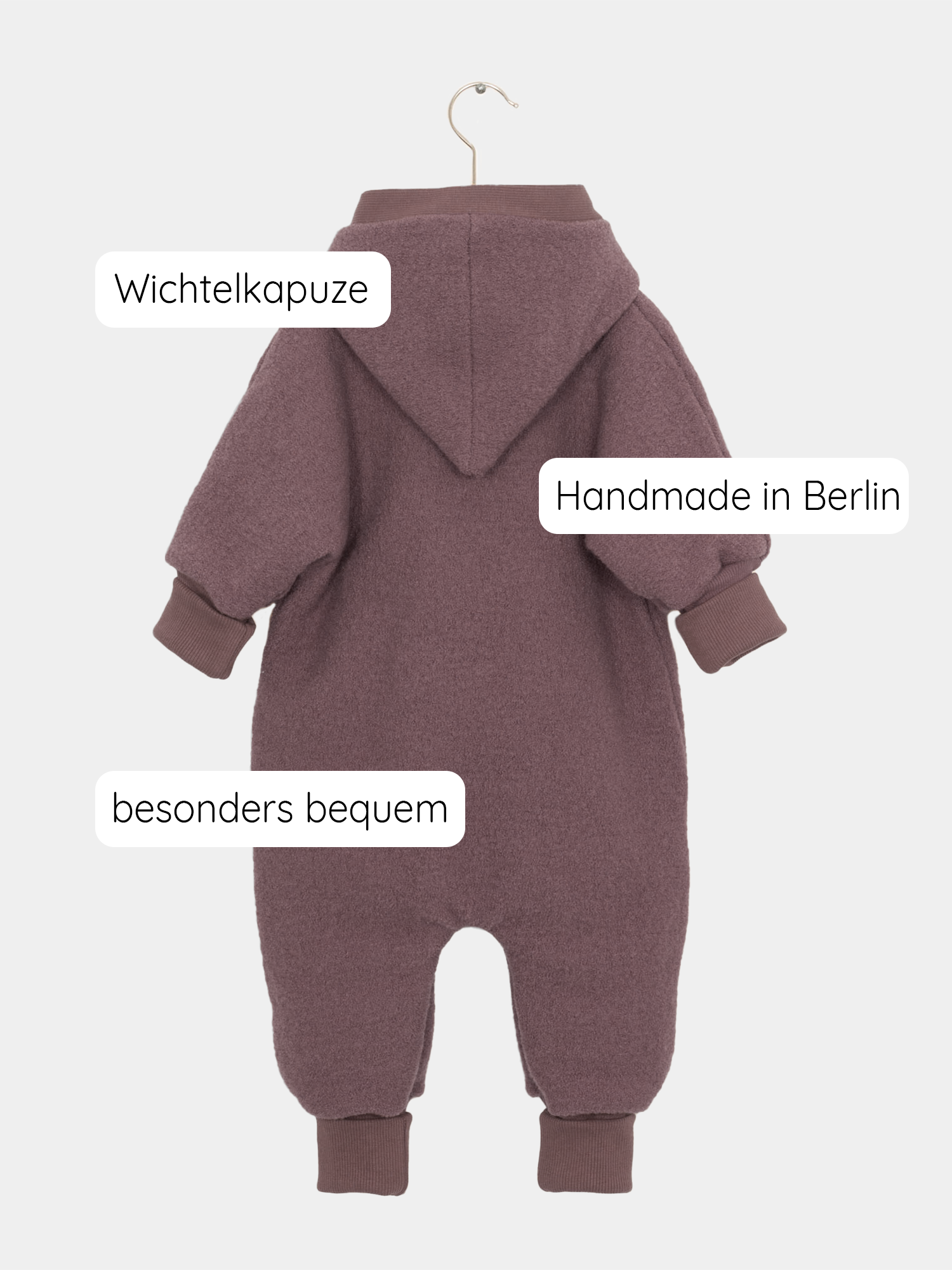 Kuschelanzug Wollwalk - Malve: Nahaufnahme eines Babysuits mit Kapuze, eng anliegenden Bündchen und Logo-Detail, ideal für kühle Monate, da er Wärme speichert und Bewegungsfreiheit bietet. Wollwalk Anzug, Wollwalk Overall für Kinder,