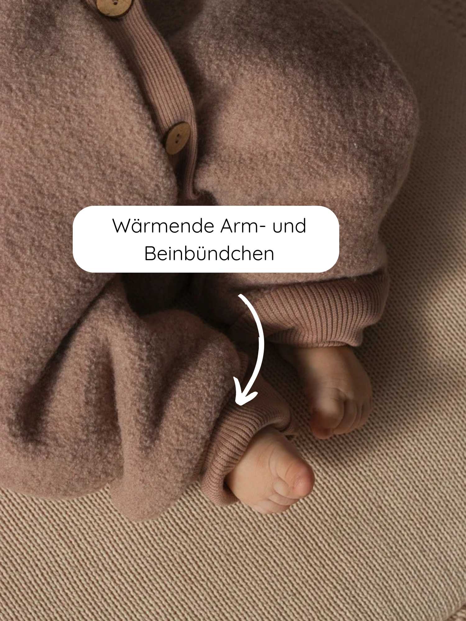 Nahaufnahme von Babyfüßen in einem Winter Wollwalk Overall mit Teddyfutter - Puder, zeigt weiche, braun-beige Fleece mit gerippten, wärmenden Beinbündchen, betont durch Text und Pfeil.