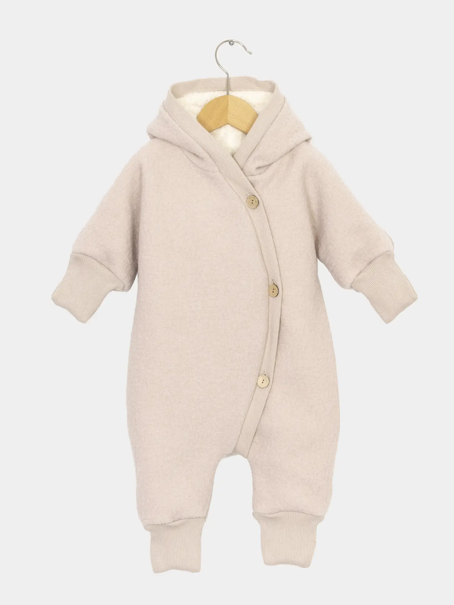 Teddy-Kuschelanzug Wollwalk - Sand: Baby-Einteiler mit Kapuze, langen Ärmeln und Knopfleiste, aus weichem Wollwalk und Teddyfutter, auf einem kleinen Holzkleiderbügel präsentiert. Ideal für kalte Tage.