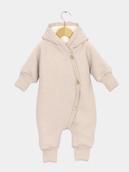 Teddy-Kuschelanzug Wollwalk - Sand: Schneeanzug für Kinder und Babys mit Kapuze, langen Ärmeln und Knopfleiste, aus weichem Wollwalk und Teddyfutter, auf einem kleinen Holzkleiderbügel präsentiert. Ideal für kalte Tage.