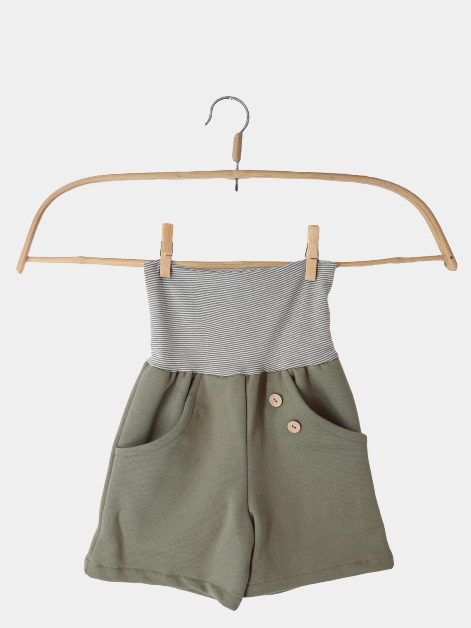 Kurze Buxe Bio-Sweat- Pistazie, bequeme Kinder-Shorts aus Bio-Sweat mit Ringelbündchen, auf einem Kleiderbügel präsentiert. Ideal für Sommer, nachhaltig in Berlin genäht, robust und weich.