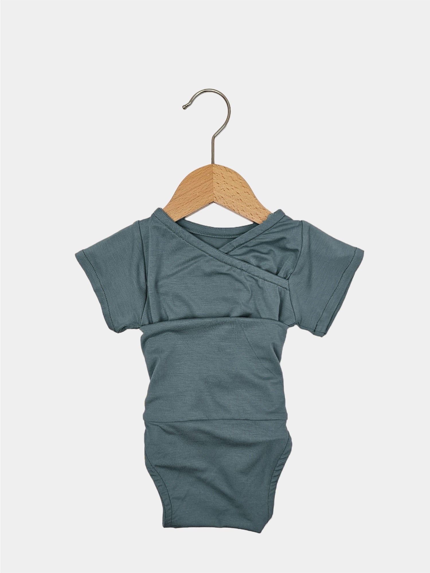 Kurzarm Loopbody Bambusviskose Aquamarin Gr. 1Y, neu, auf einem Holzkleiderbügel. Zeigt ein schlichtes Design mit kurzen Ärmeln und weichem Stoff, ideal für Babys im ersten Lebensjahr.