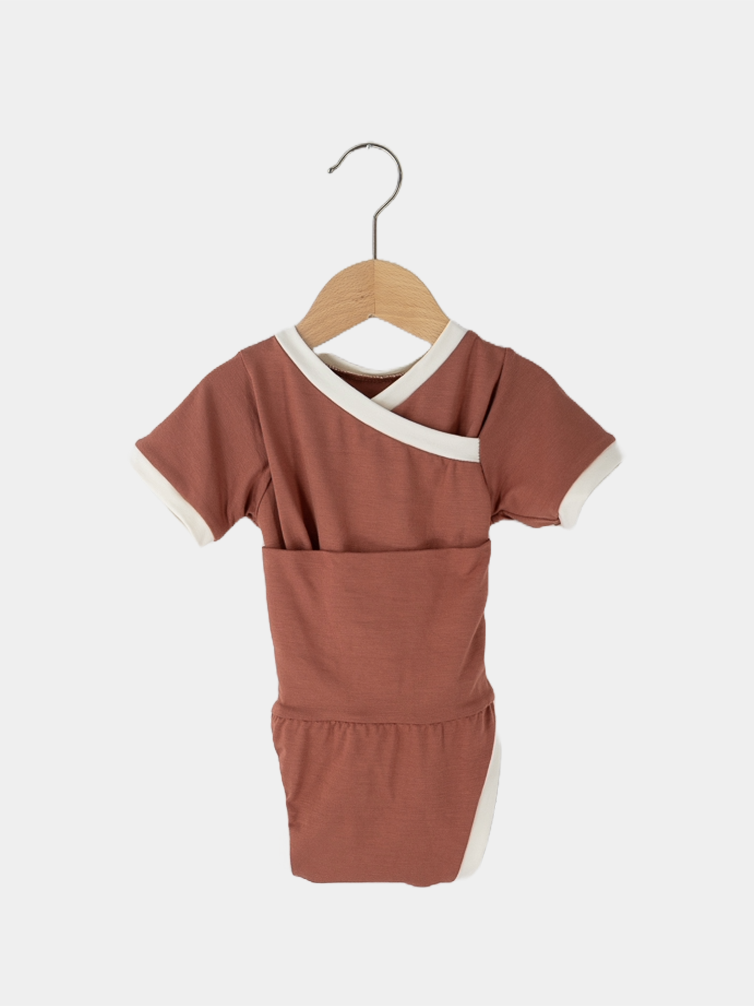 Kurzarm Loopbody Bambusviskose - Pfirsich auf einem Holzkleiderbügel. Der Body ohne Knöpfe bietet weiche, elastische Passform, ideal für den Sommer. Perfekt für Garten und Strand, atmungsaktiv und schnelltrocknend.