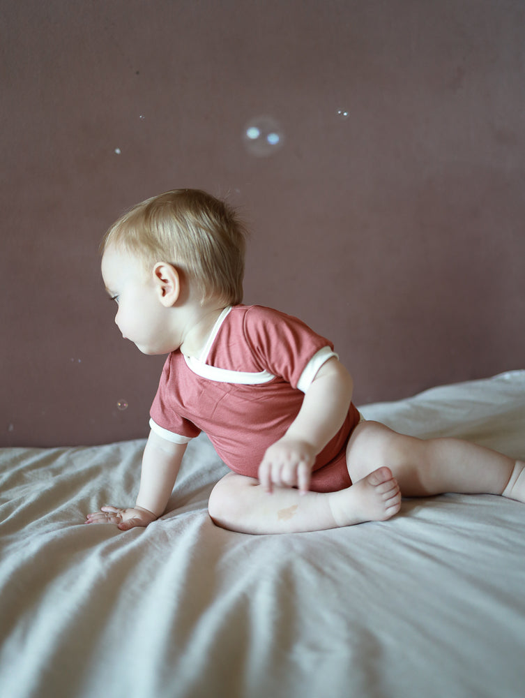 Kurzarm Loopbody Bambusviskose - Pfirsich: Ein weicher, elastischer Babybody ohne Knöpfe, mit kurzem Arm und innovativem Loop-Design, das bequem um den Bauch liegt und schnelles Anziehen ermöglicht.