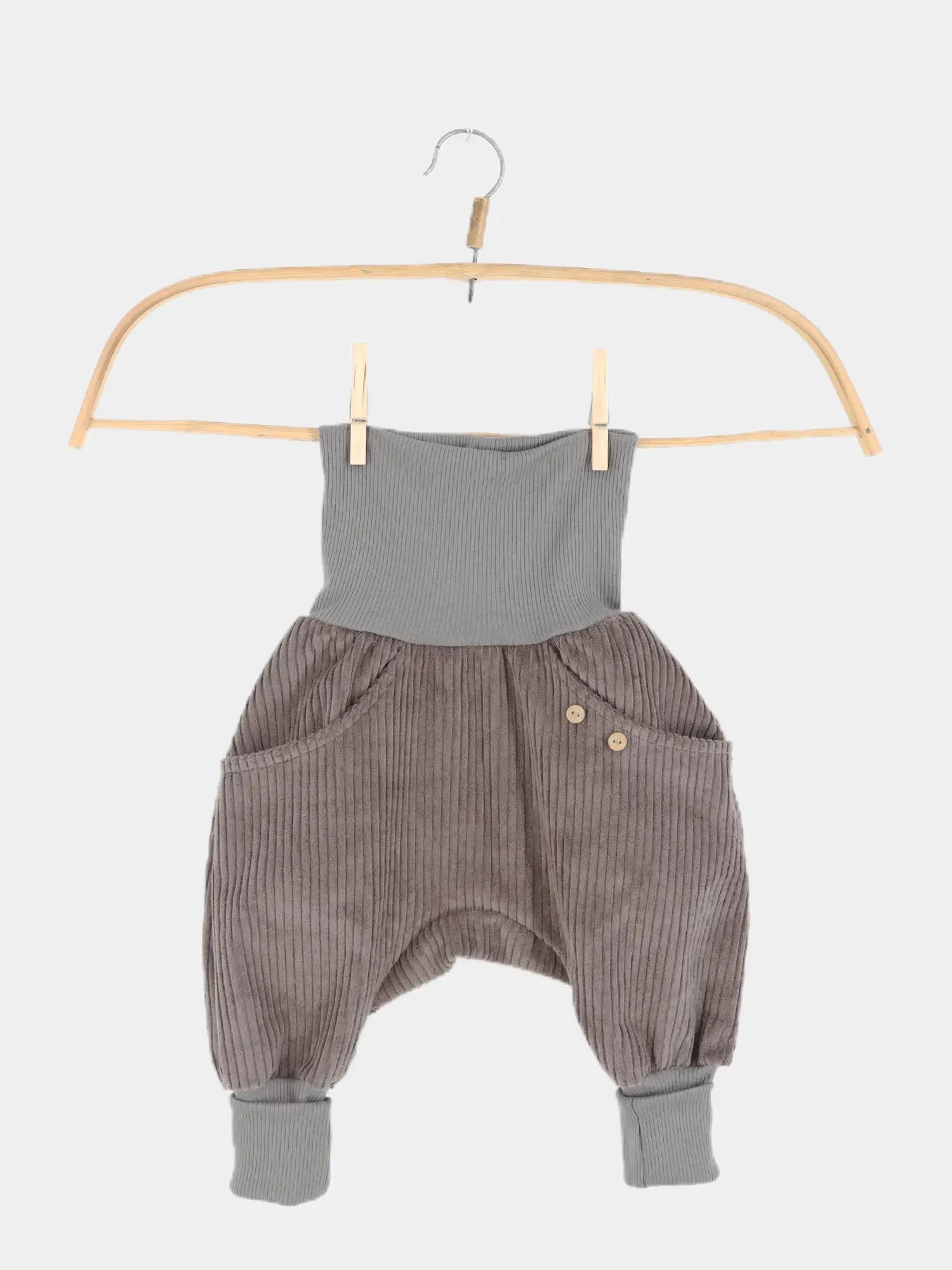 Knickerbocker Breitcord - Praline: Kinderharemshose aus grauem Cordstoff, mit hohem Strickbund und Bündchen, zwei Fronttaschen mit Holzknöpfen, an Holzkleiderbügel mit Wäscheklammern befestigt.