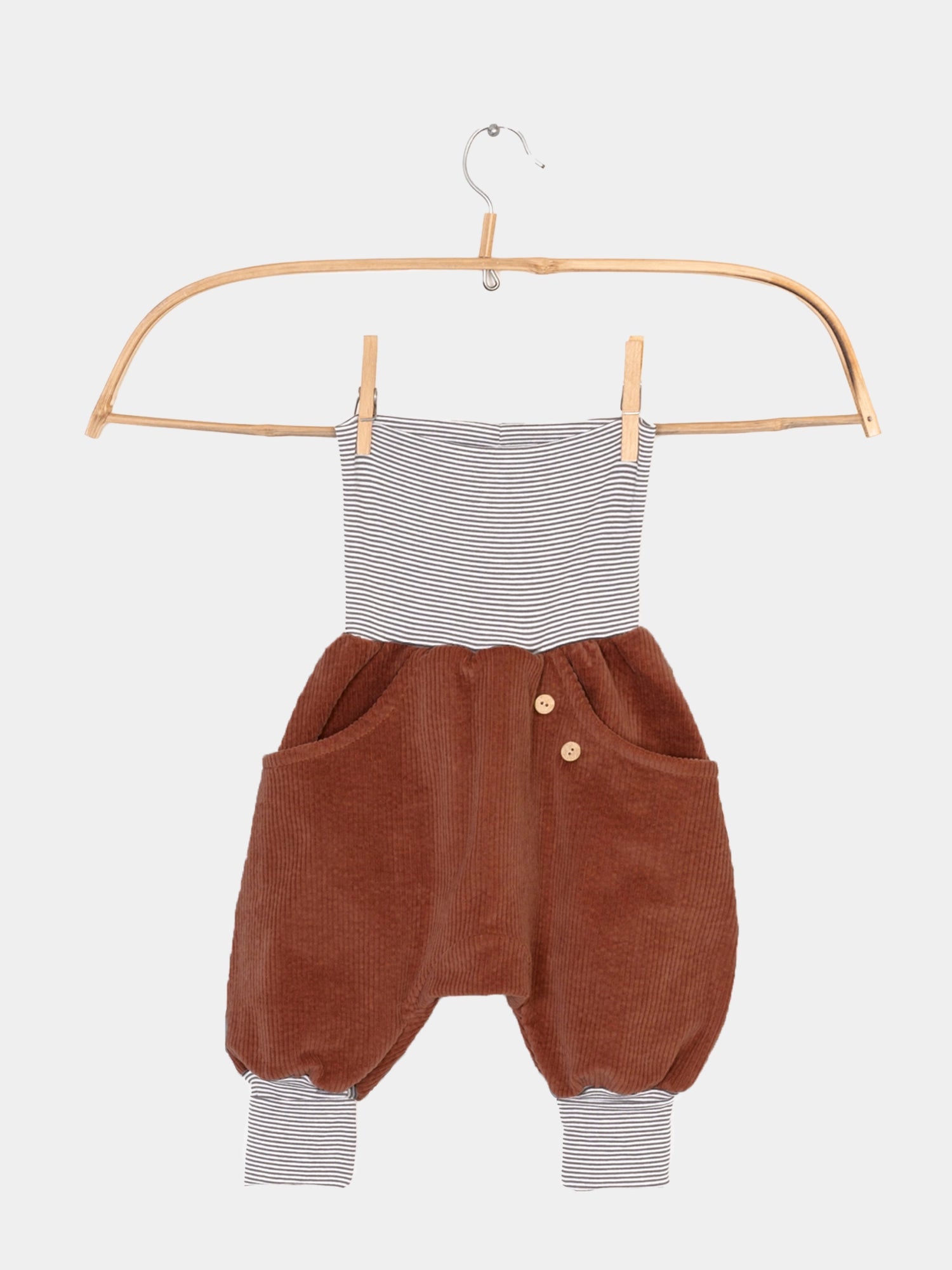 Knickerbocker Breitcord mit Ringelbündchen - Rost auf einem Kleiderbügel, kombiniert mit einem gestreiften Oberteil. Cordhose mit Knöpfen und großer Känguru-Tasche, bekannt für Bewegungsfreiheit und Komfort.