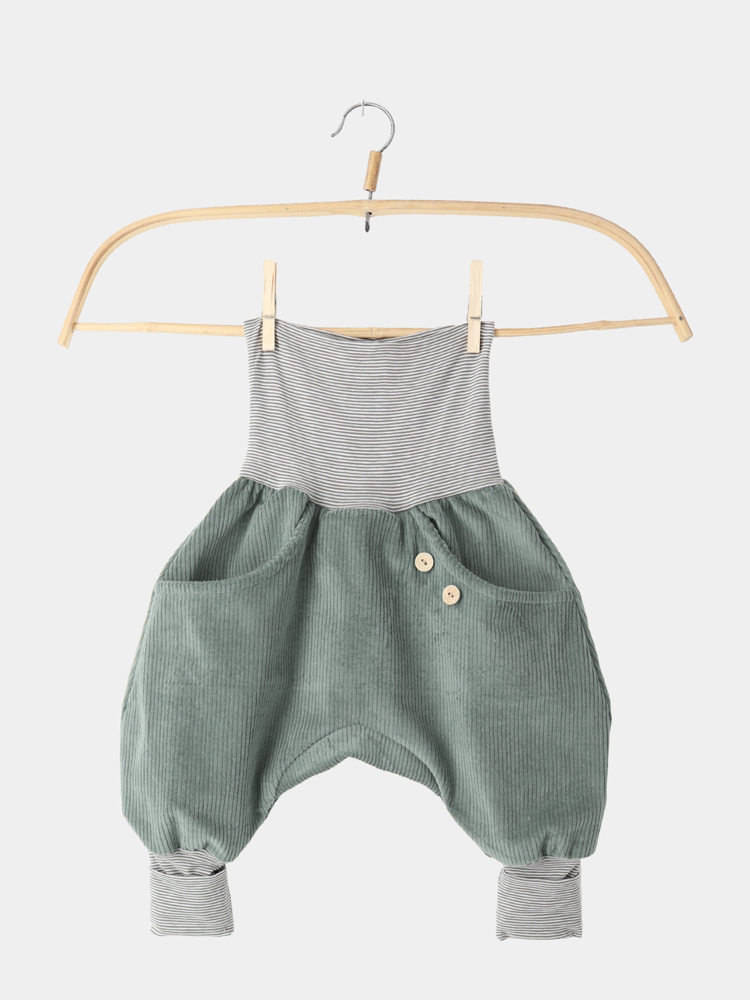 Knickerbocker Breitcord Stretch mit Ringelbündchen - Aqua: Kinder-Romper aus sage-grünem Cord mit grauen, gestreiften Bündchen. Zwei vordere Taschen, eine mit Holzknöpfen, auf einem Holzkleiderbügel hängend.