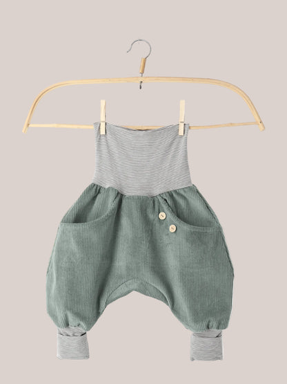 Knickerbocker Breitcord Stretch mit Ringelbündchen - Aqua: Kinder-Romper aus sage-grünem Cord mit grauen, gestreiften Bündchen. Zwei vordere Taschen, eine mit Holzknöpfen, auf einem Holzkleiderbügel hängend.