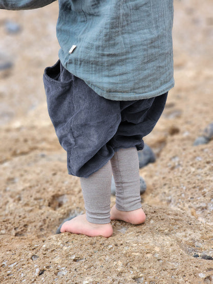 Knickerbocker Feincord Ringel - Blaubeere: Nahaufnahme eines Kindes, das barfuß auf sandigem Boden steht, trägt weiche, dunkelgraue Cordhose mit gestreiftem Bund, ideal für bequeme Bewegungsfreiheit.