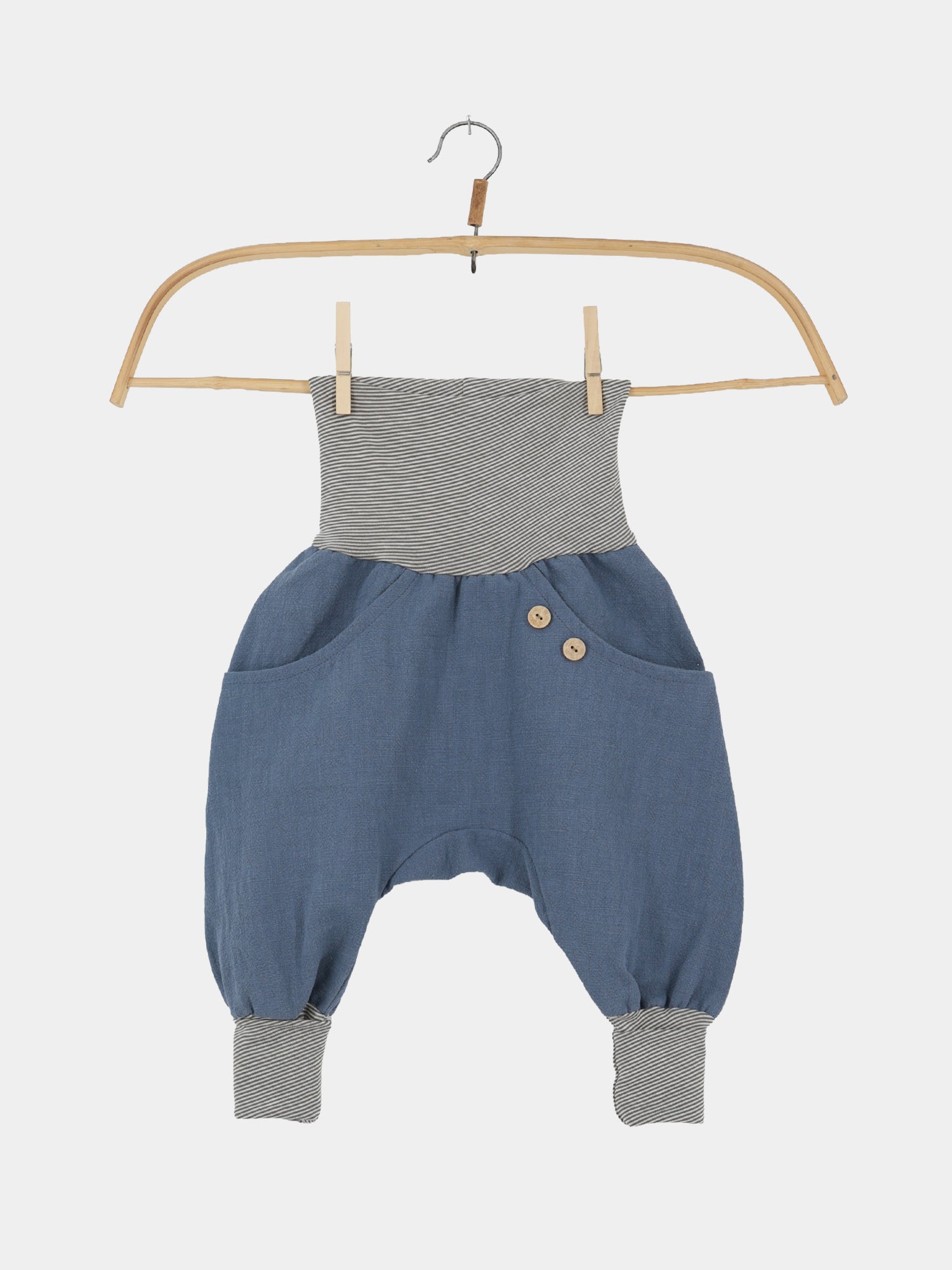 Knickerbocker Leinen - Blaubeere: Locker geschnittene, harem-stil Babyhose mit weichem, schieferblauen Stoff, grauweiß gestreiftem Bund, Holzknöpfen und Seitentaschen, auf Holzkleiderbügel präsentiert. Handgefertigt in Berlin.