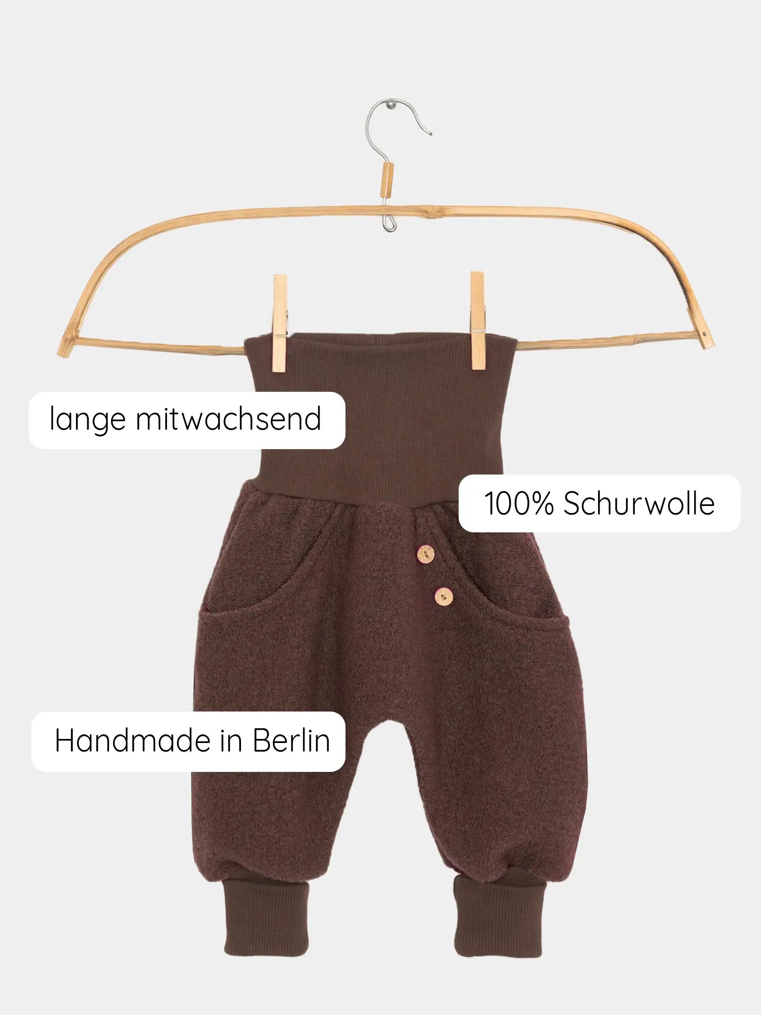 Knickerbocker Wollwalk - Schoko aus 100 % Schurwolle, hängend an einem Holzkleiderbügel mit Kängurutaschen, Holzknöpfen, breitem Bündchen und gerippten Beinabschlüssen. Handgemacht in Berlin, ideal für kaltes Wetter.