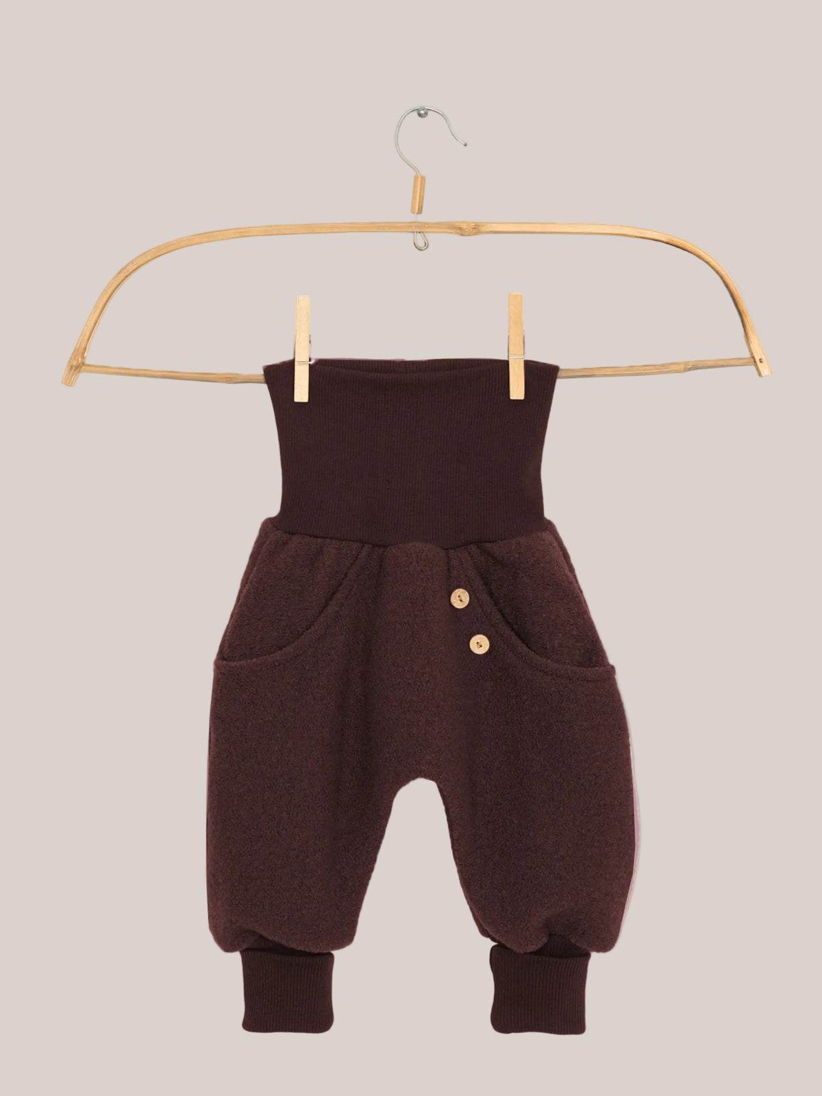 Knickerbocker boiled-wool pants – Chocolate: Small harem-style pants with a high ribbed waistband, side pockets with wooden buttons, soft wool fabric, and ribbed ankle cuffs, hanging on a wooden clothes hanger.