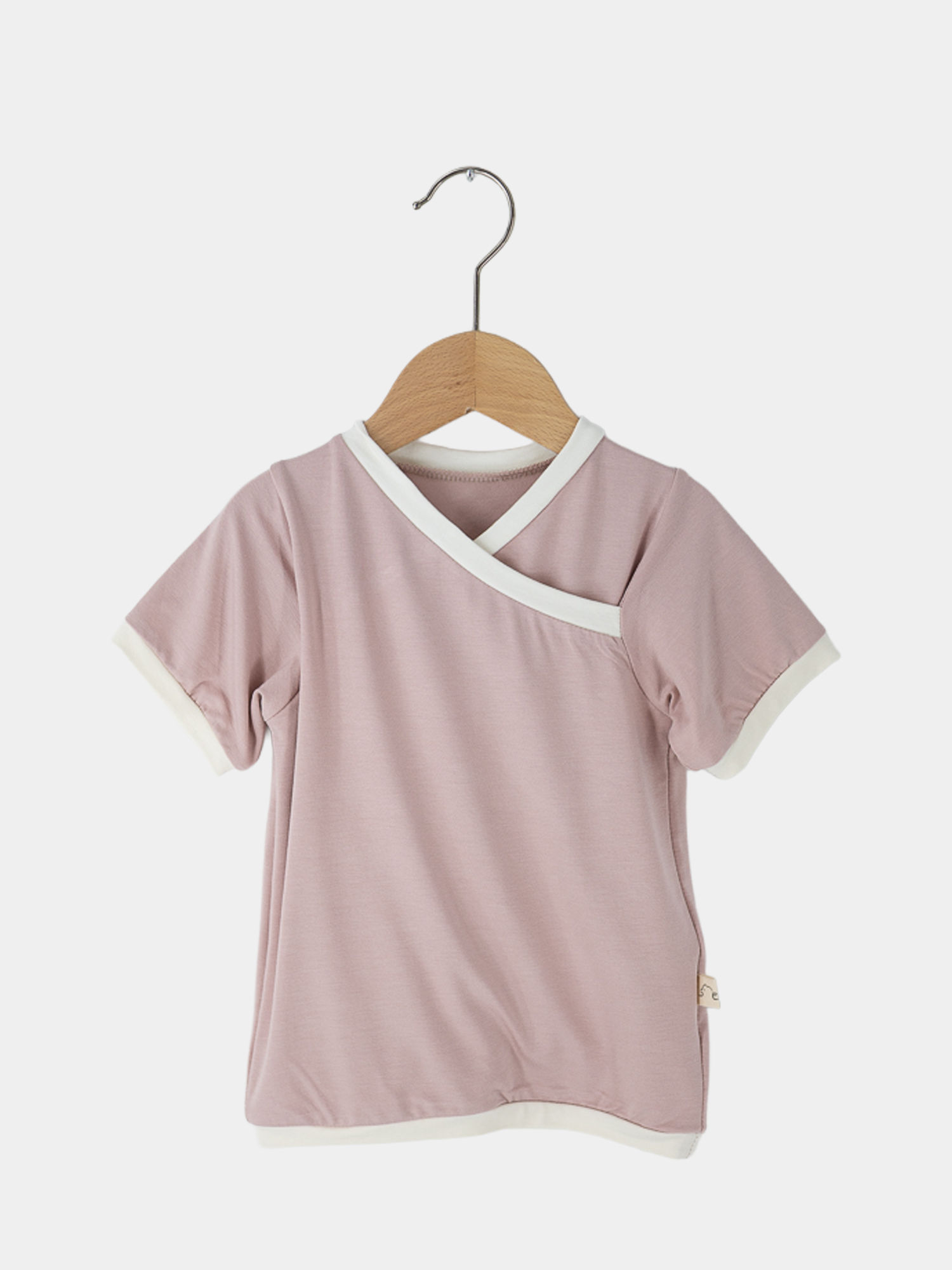 Kurzes Wickelshirt Bambusviskose - Rosa auf einem Holzkleiderbügel. Locker sitzend, mit schlauem Wickelausschnitt, ideal für Sommeraktivitäten. Handgenäht in Berlin, geeignet für 2-3 Jahre.