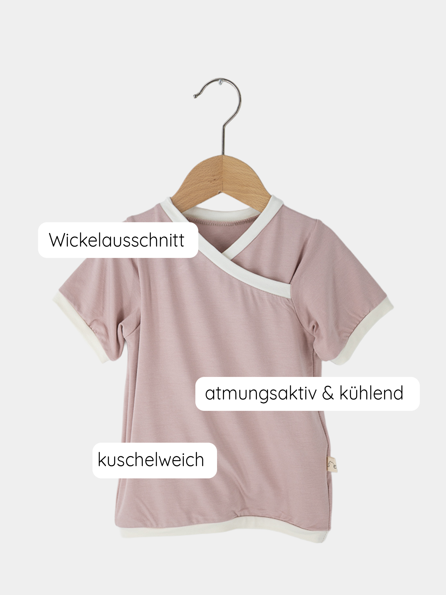 Kurzes Wickelshirt Bambusviskose - Rosa auf einem Holzbügel. Das Shirt hat einen cleveren Wickelausschnitt, ideal für Kinder im Alter von 2-3 Jahren, handgenäht in Berlin.