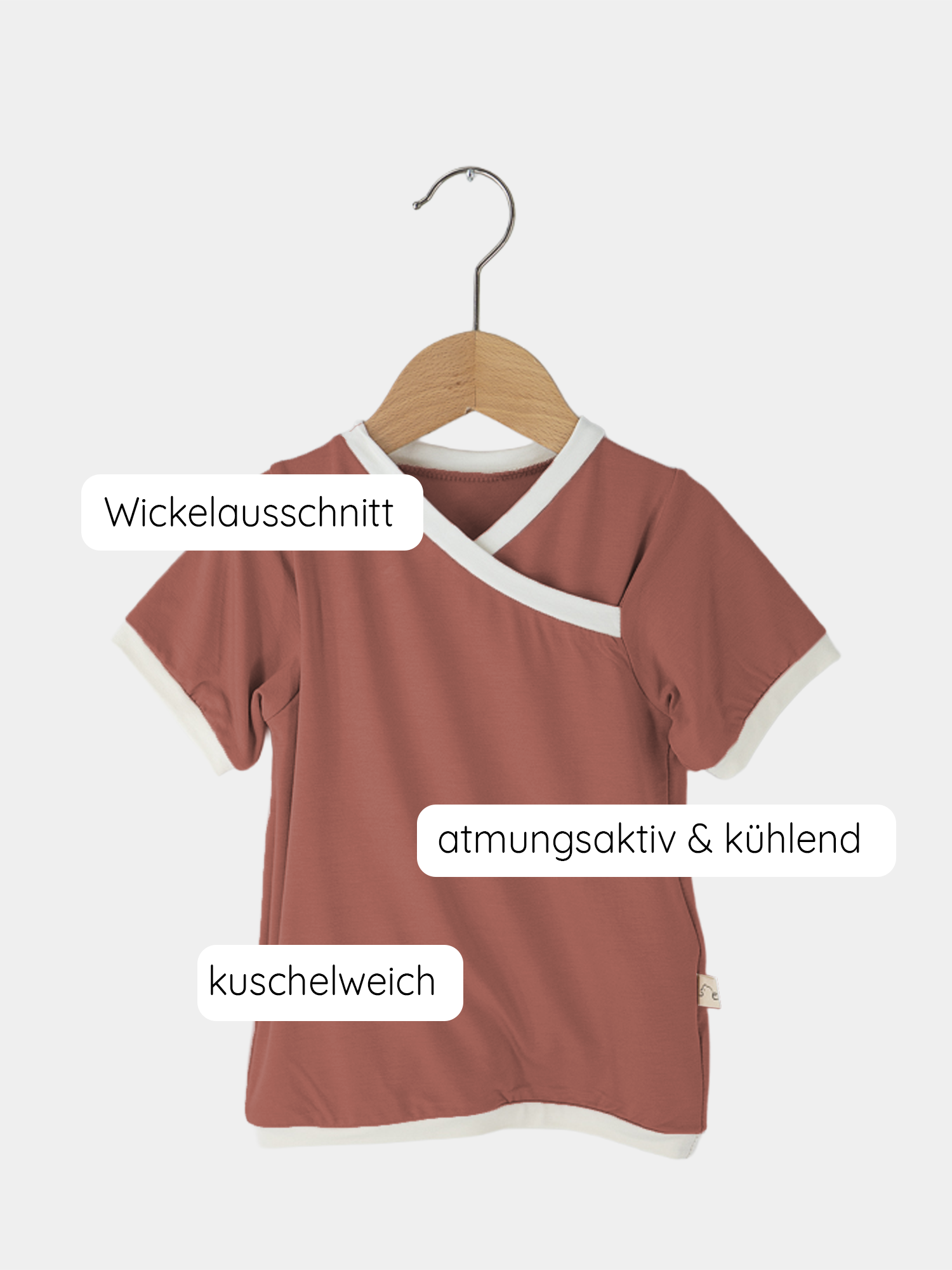Nahaufnahme des Kurzes Wickelshirt Bambusviskose - Pfirsich auf einem Kleiderbügel, zeigt den Wickelausschnitt. Ideal für Sommer, schnell trocknend, antibakteriell. Handgenäht in Berlin, für 2-3 Jahre geeignet.