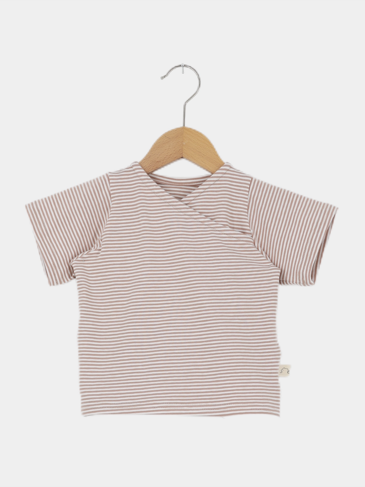 Kurzes Wickelshirt Baumwolle - Ringel Weizen, ein kurzärmeliges, gestreiftes Oberteil im Wickelstil, hängt auf einem Holzkleiderbügel. Es ist weich, bequem und aus Ökotex-zertifizierter Baumwolle handgemacht in Berlin.