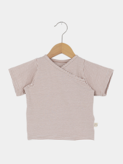 Kurzes Wickelshirt Baumwolle - Ringel Weizen, ein kurzärmeliges, gestreiftes Oberteil im Wickelstil, hängt auf einem Holzkleiderbügel. Es ist weich, bequem und aus Ökotex-zertifizierter Baumwolle handgemacht in Berlin.
