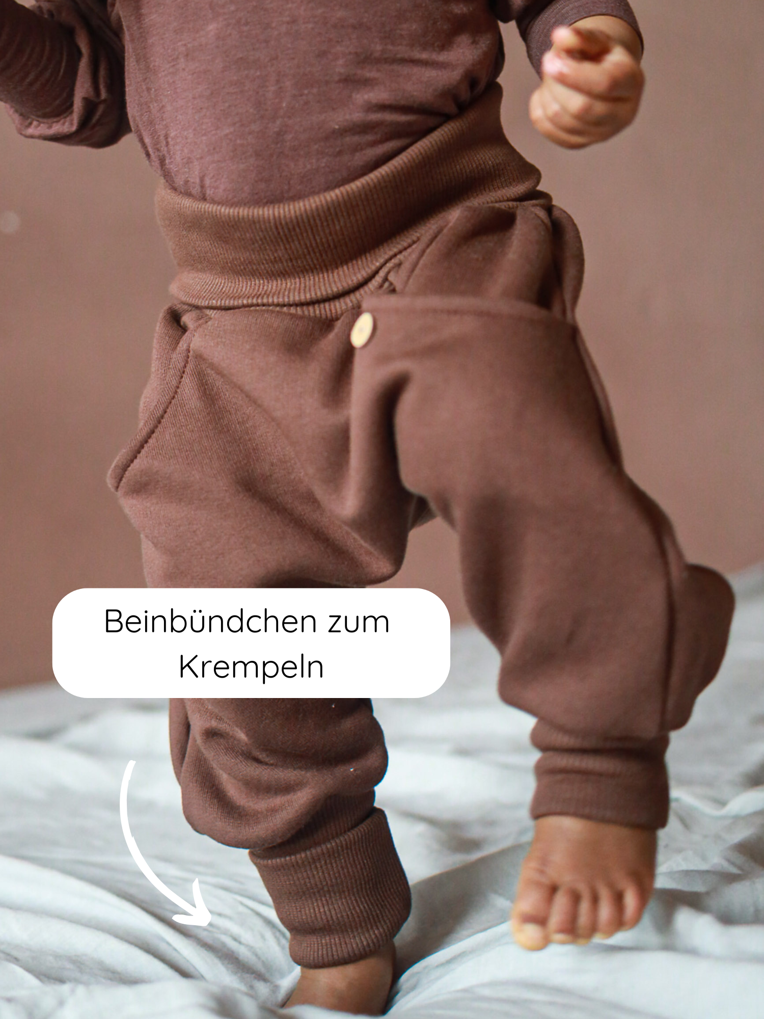 Kleinkind trägt Knickerbocker Bio-Sweat - Schoko mit umgeschlagenen, gerippten Beinbündchen. Nahaufnahme zeigt die lockere Passform und das praktische, elastische Bündchen für Komfort und Bewegungsfreiheit.