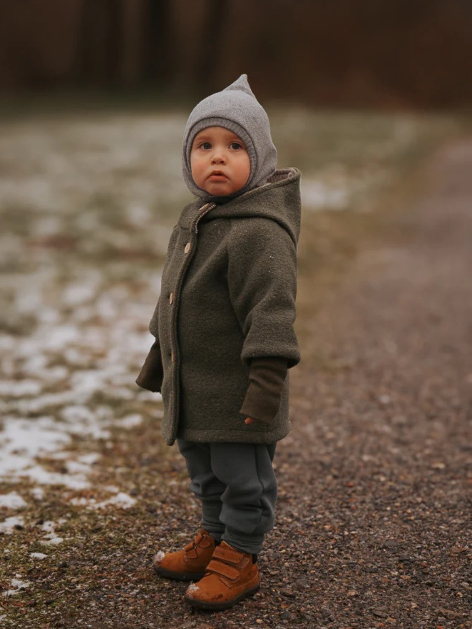 Ein Kind auf einem verschneiten Weg trägt Knickerbocker Bio-Sweat - Taube, eine gemütliche Hose aus weichem Bio-Sweat mit elastischem Bund, ideal für Bewegungsfreiheit und Komfort.