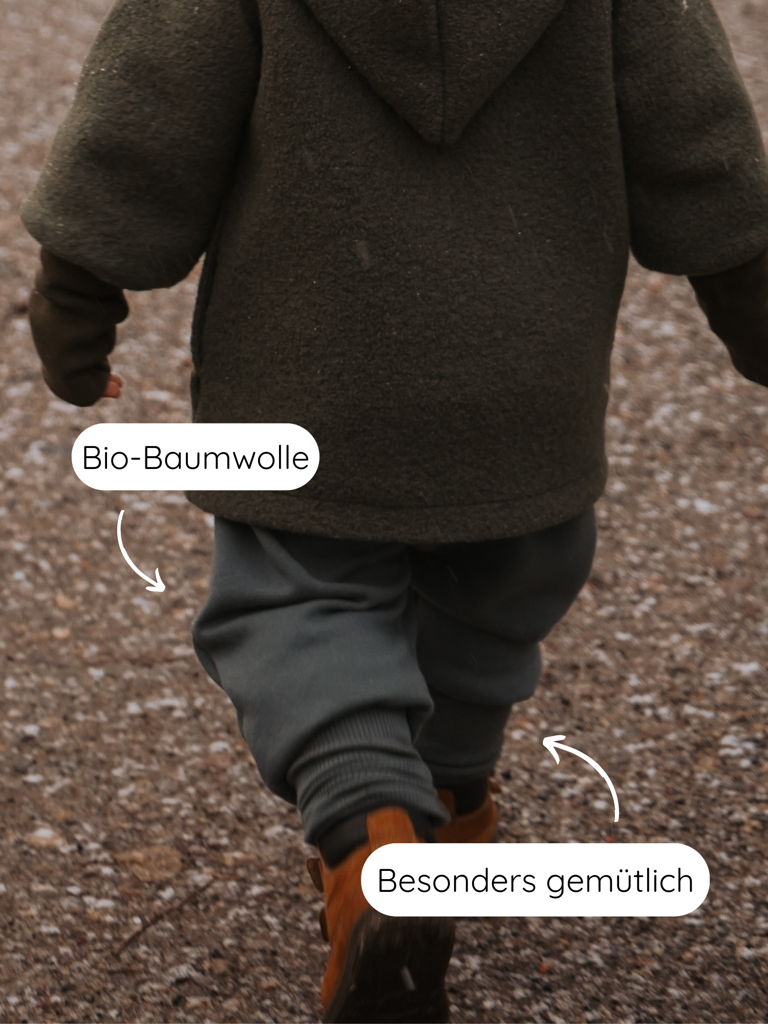 Ein Kleinkind in Knickerbocker Bio-Sweat - Taube läuft auf einem Kiesweg, getragen mit olivgrüner Kapuzenjacke und braunen Stiefeletten. Kleidung aus weicher Bio-Baumwolle, besonders gemütlich und atmungsaktiv.