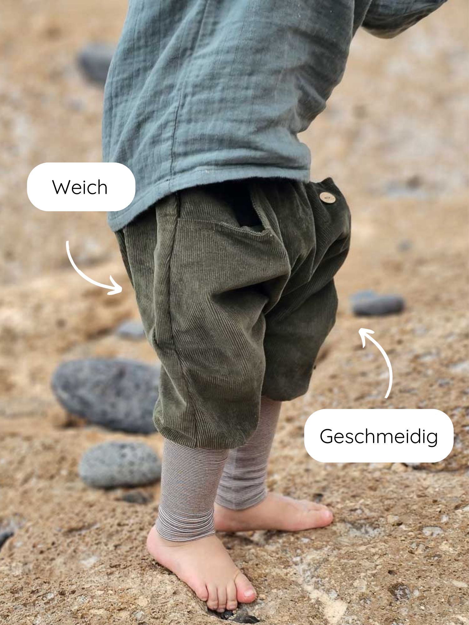 Kleinkind steht barfuß auf Kieselsand, trägt Knickerbocker Feincord Ringel - Avocado. Die weichen, geschmeidigen Cordhosen bieten Bewegungsfreiheit, ideal für aktive Kinder. Cordhosen über gestreiften Leggings sichtbar.