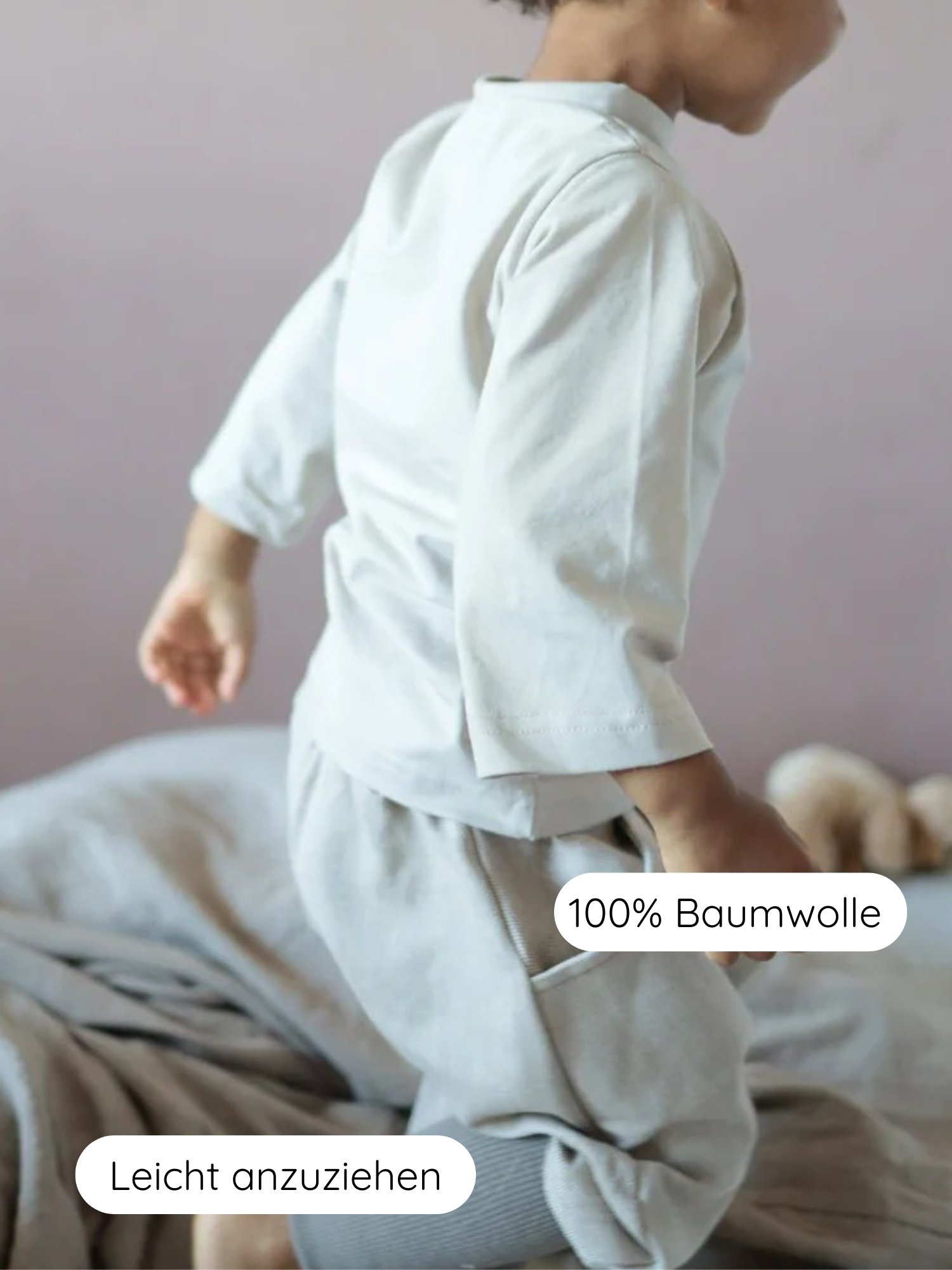 Ein Kleinkind steht auf einem Bett in hellen, lockeren Knickerbocker Feincord Ringel - Sand, gefertigt aus 100 % Baumwolle mit gestreiftem Bund; ideal für aktive, spielende Kinder.