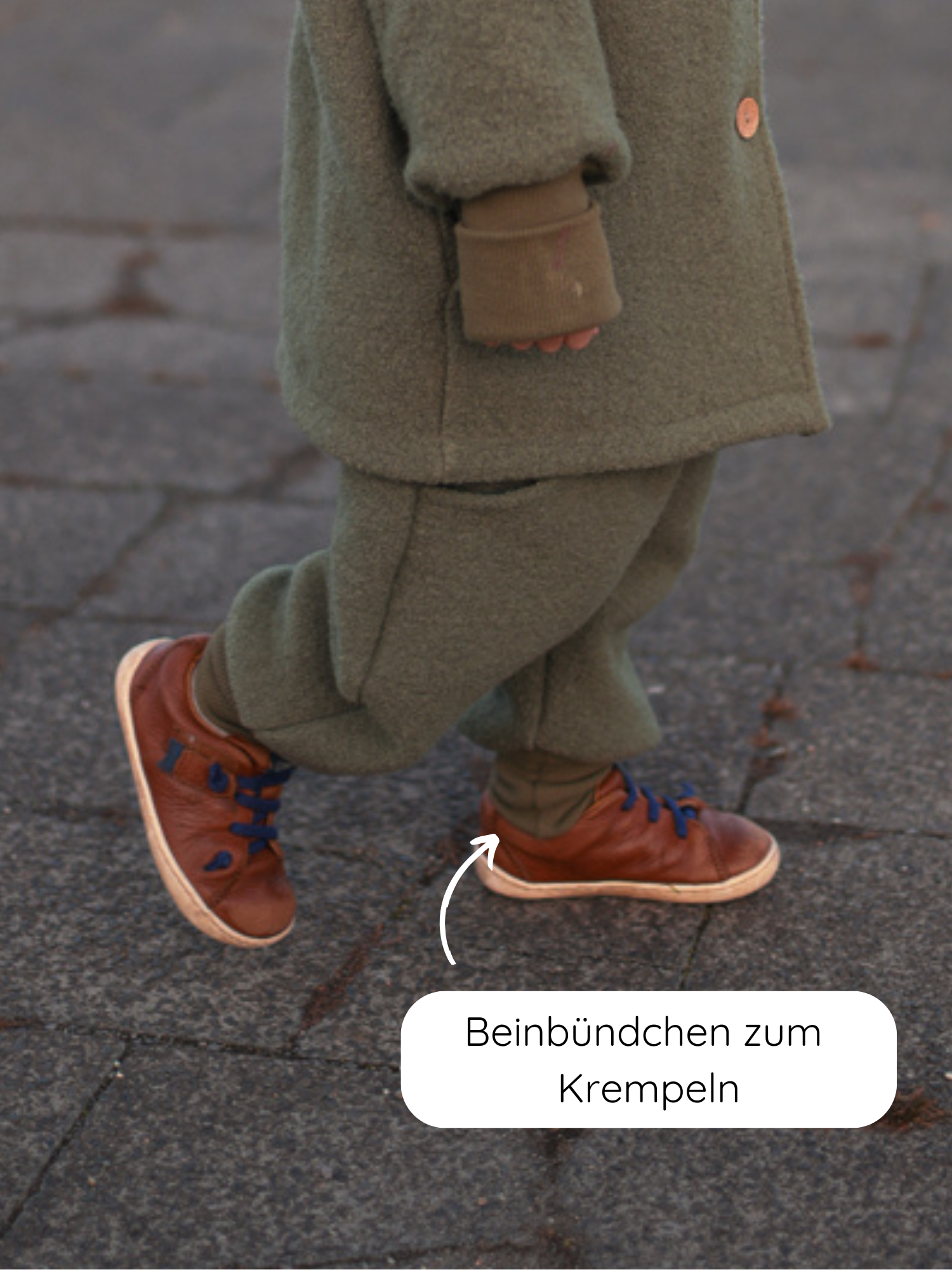 Knickerbocker Wollwalk - Pistazie: Kleinkind trägt olivgrünes Wollwalk-Outfit mit braunen Ledersneakern. Elastische Beinbündchen zum Krempeln sichtbar, ideal für Anpassungen und mitwachsend. Perfekt für kaltes, nasses Wetter.
