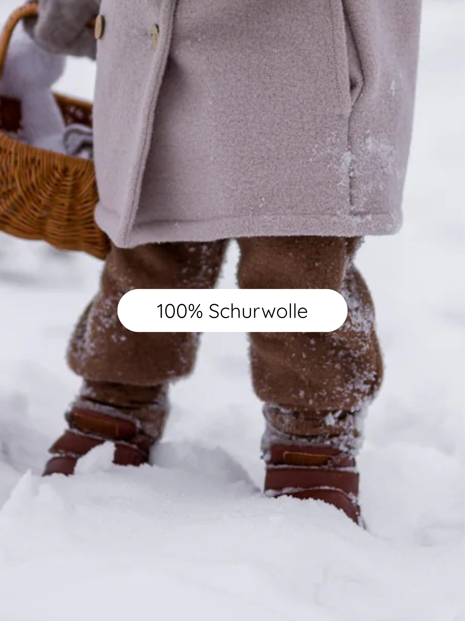 Knickerbocker Wollwalk - Schoko: Ein Kind trägt eine Wollwalk-Hose mit Kängurutaschen und Bio-Baumwollbündchen, kombiniert mit einem Wollmantel und braunen Lederstiefeln, während es einen gefütterten Korb hält.