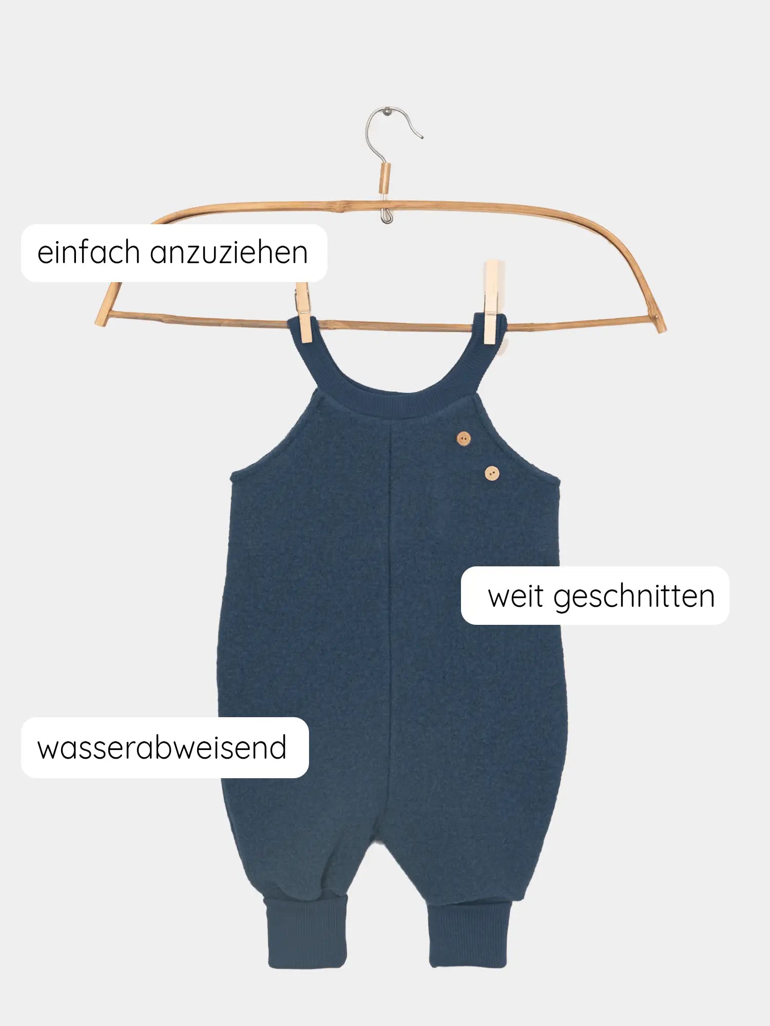 Schlupflatzhose Wollwalk aus 100% Schurwolle - Marine: Dunkelblauer Kinder-Romper aus Wollwalk, weit geschnitten, einfach anzuziehen und wasserabweisend, auf einem Holzkleiderbügel hängend, ideal für Herbst- und Winterabenteuer.