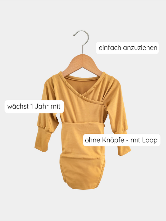 Loopbody Bambusviskose - Honig: Ein mustard-gelber, langärmeliger Babybody ohne Knöpfe, mit innovativem Loop-Verschluss auf einem Holzkleiderbügel. Hervorgehoben sind einfach anzuziehen, mit Loop und wächst 1 Jahr mit.