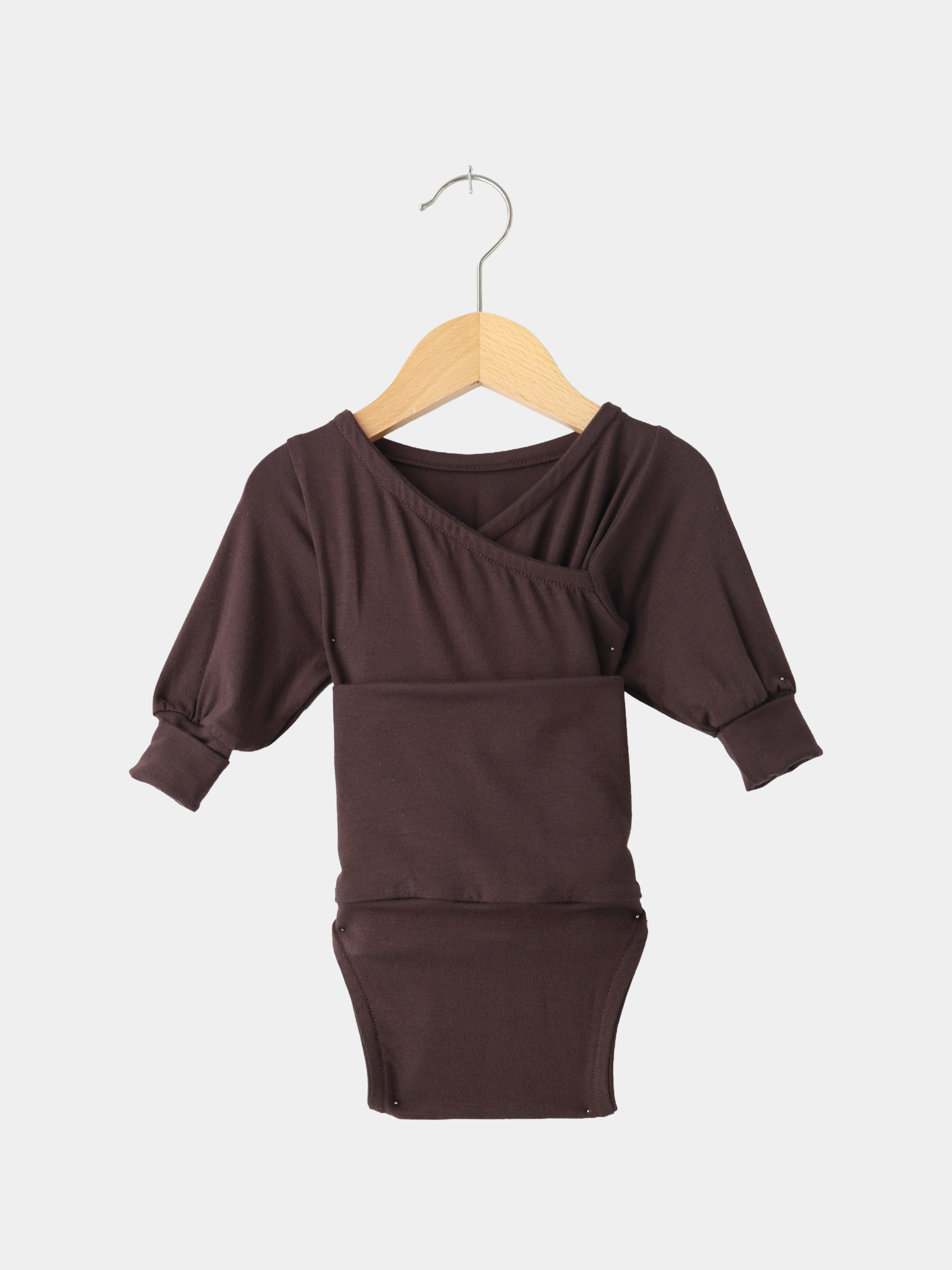 Loopbody Bambusviskose - Zartbitterschokolade: Langärmeliger, tiefbrauner Babybody im Wickelstil mit Rippenbündchen und Druckknöpfen am Schritt, präsentiert auf einem Holzkleiderbügel vor weißem Hintergrund.
