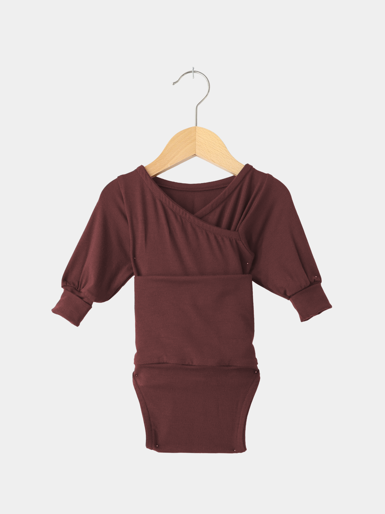 Loopbody Bambusviskose - Burgund: Kinder-Body in tiefem Burgunderrot, langärmelig mit kimonoartigem Ausschnitt und Druckknöpfen am Saum, präsentiert auf einem Holzkleiderbügel. Ideal für wachsendes Baby, atmungsaktiv und weich.