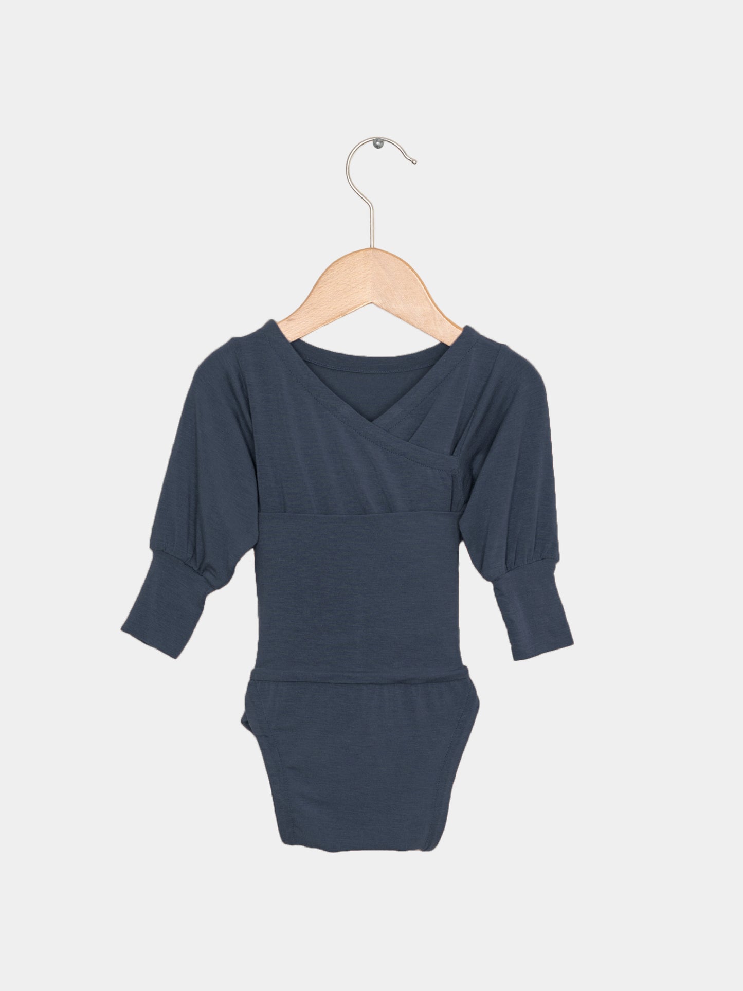 Loopbody Kaschmir-Mix - Blaubeere: Langarm-Babybody mit Wickelausschnitt, an einem Holzkleiderbügel hängend. Der Body ist aus weichem Kaschmir-Mix, ohne Knöpfe, ideal für zarte Babyhaut.