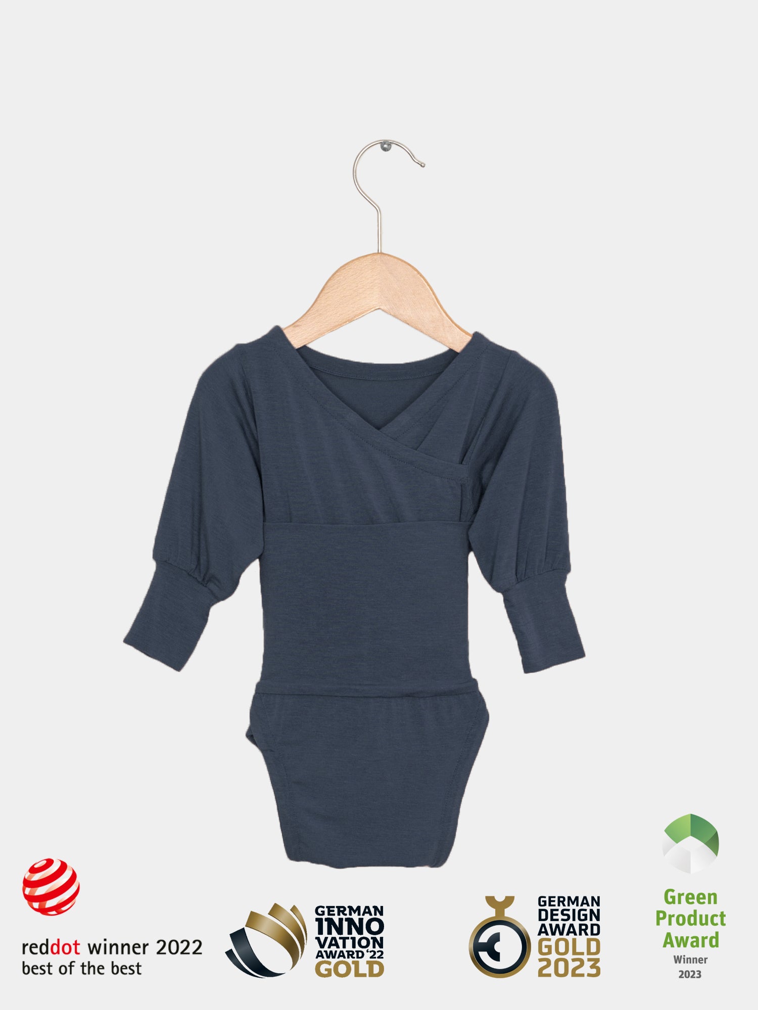 Loopbody Kaschmir-Mix - Blaubeere: Dunkelblauer Langarm-Babybody aus Kaschmir-Mix, auf einem Holzkleiderbügel. Design und Nachhaltigkeit ausgezeichnet mit Red Dot, German Innovation und Design Awards.