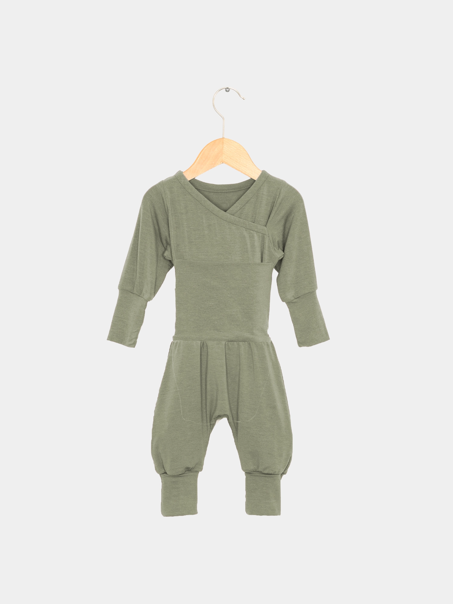 Loopstrampler Kaschmir-Mix - Pistazie: Langärmeliger, olivgrüner Baby-Romper ohne Knöpfe aus weichem Kaschmir-Micromodal-Mix, hängend an einem Holzbügel. Ideal für sanftes Wickeln und maximalen Tragekomfort.