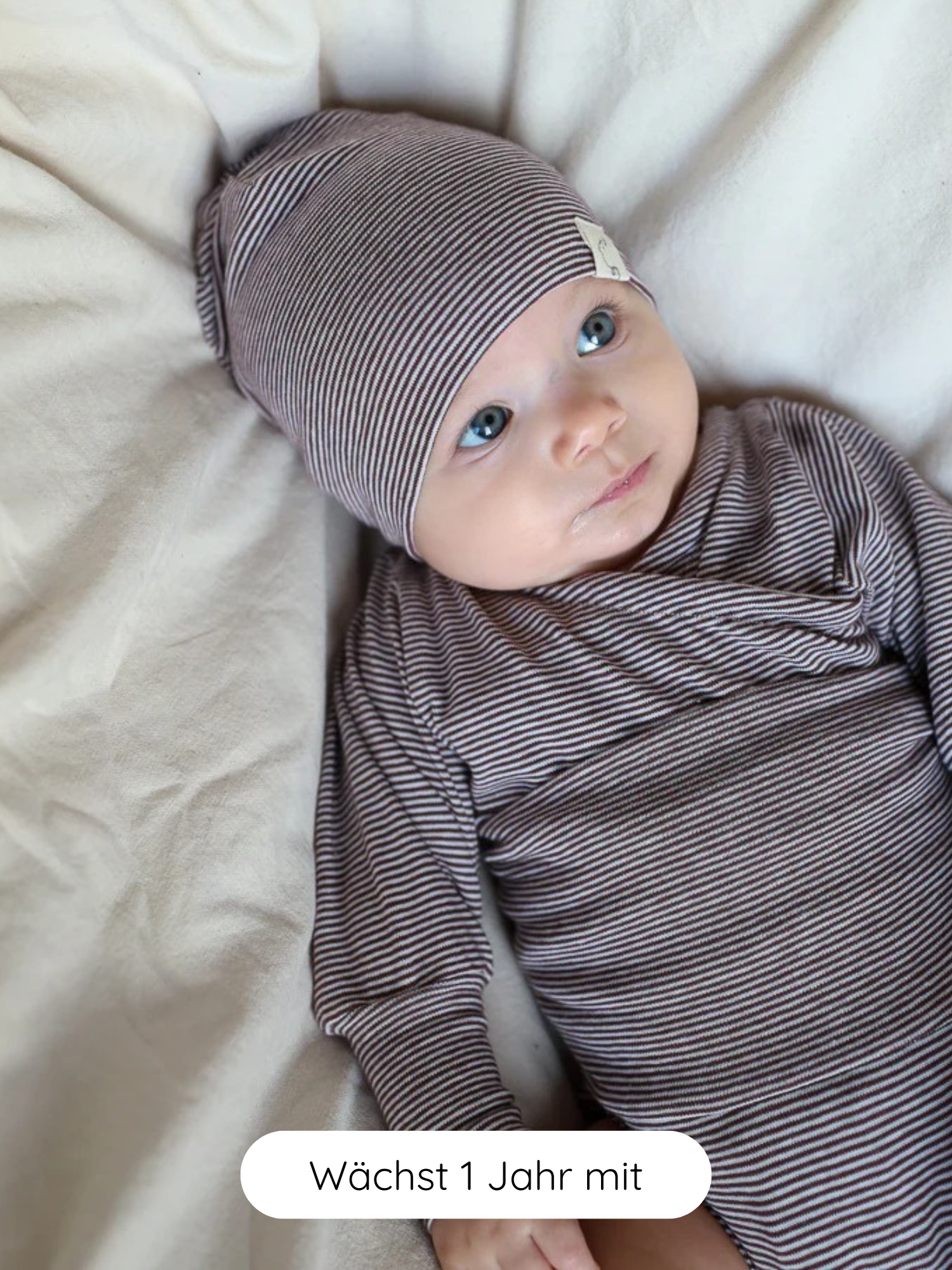 Ein Baby trägt den Loopbody Bio-Baumwolle-Ringel Schoko, einen fein gestreiften Babybody mit passender Knotenmütze, der für Nachhaltigkeit steht und für ein Jahr mitwächst.
