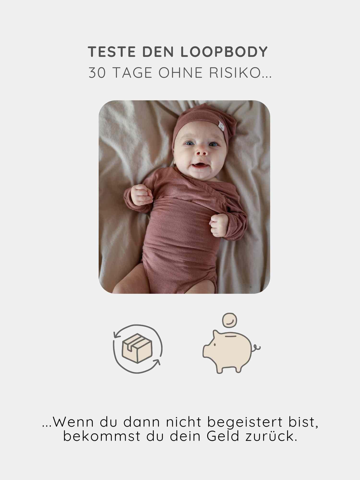 Ein lächelndes Baby liegt in einem Loopbody Kaschmir-Mix - mitwachsender Babybody - Zimt, eingehüllt in einen weichen Staubrosen-Wickelbody mit passendem Hut, auf einem Bett.