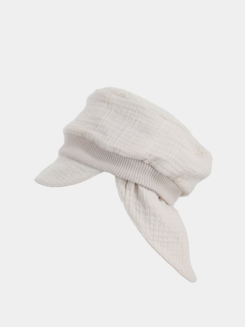 Die Michelmütze Bio-Musselin mit Nackenschutz - Sand ist eine leichte, beige Mütze im Baker-Boy-Stil mit kurzem Schirm und lockeren, schalartigen Paneelen, ideal für sommerlichen Sonnenschutz.