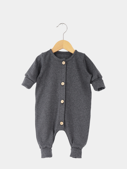 Mini Overall Feinstrick - Ruß Meliert: Dunkelgrauer langärmeliger Babystrampler mit Rundhalsausschnitt, Manschetten und vier hellen Holzknöpfen vorne, aus weichem, atmungsaktivem Feinstrick-Jersey, auf einfachem Holzkleiderbügel hängend.