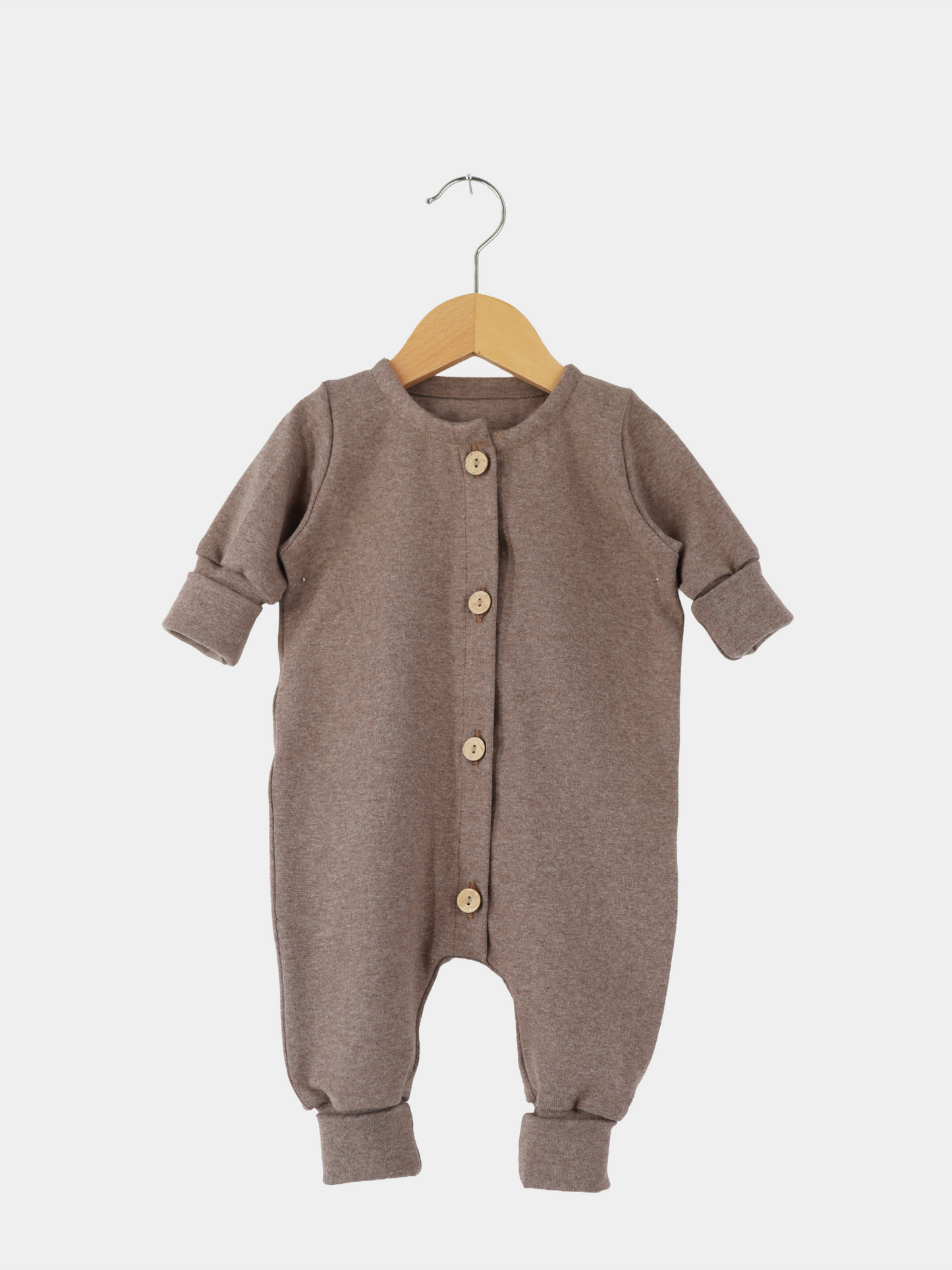 Mini Overall Feinstrick - Praline Meliert: Langarm-Strampler aus braunem Feinstrick-Jersey mit Rundhalsausschnitt, Holzknöpfen und umklappbaren Bündchen, auf Holzkleiderbügel präsentiert.