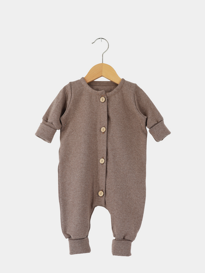 Mini Overall Feinstrick - Praline Meliert: Langarm-Strampler aus braunem Feinstrick-Jersey mit Rundhalsausschnitt, Holzknöpfen und umklappbaren Bündchen, auf Holzkleiderbügel präsentiert.